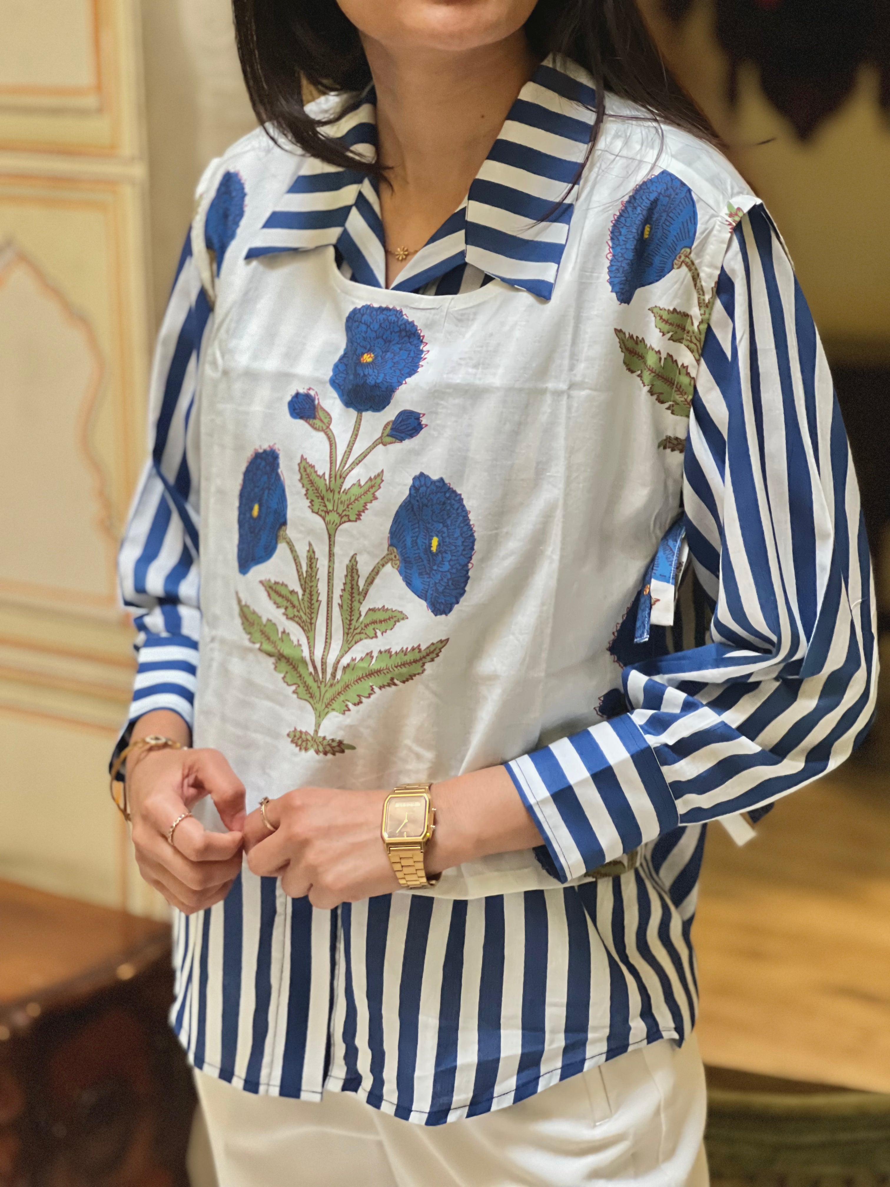 Person wearing a blue and white striped shirt with an embroidered floral apron.