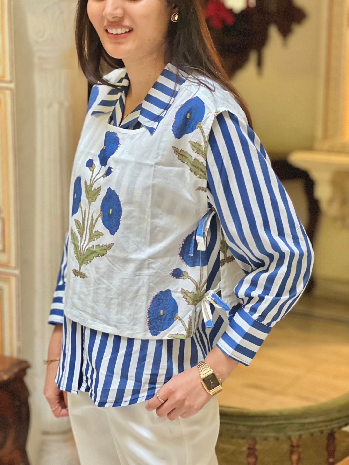 Woman wearing a blue and white striped shirt with a floral apron in an indoor setting.
