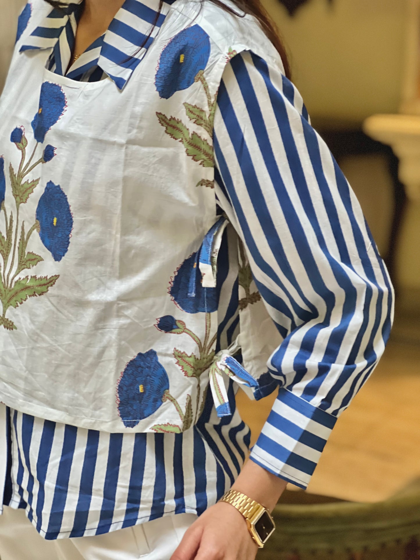 Person wearing a blue and white striped shirt with floral embroidery on a blurred background