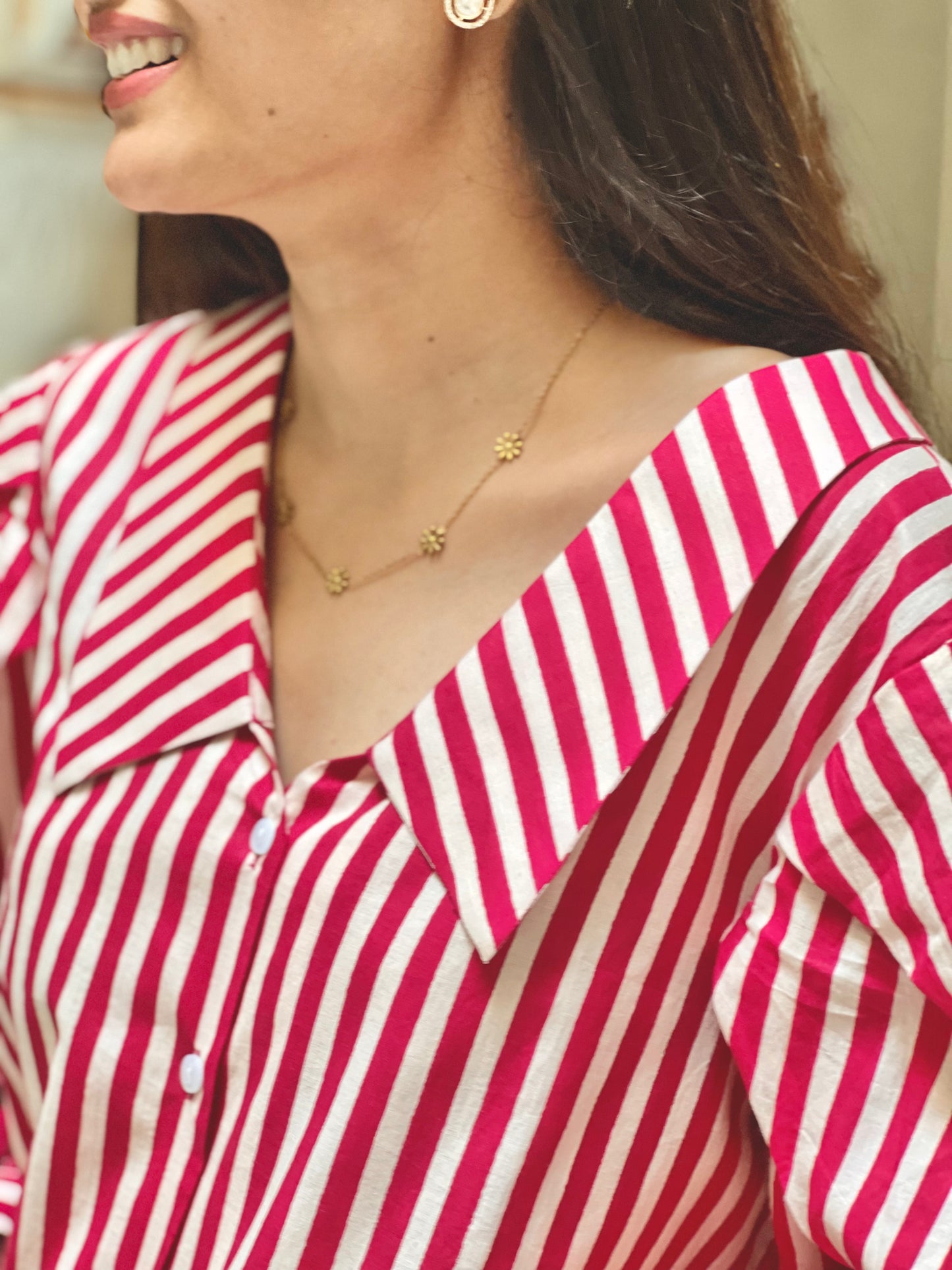 Woman wearing a red and white striped shirt with a gold necklace.