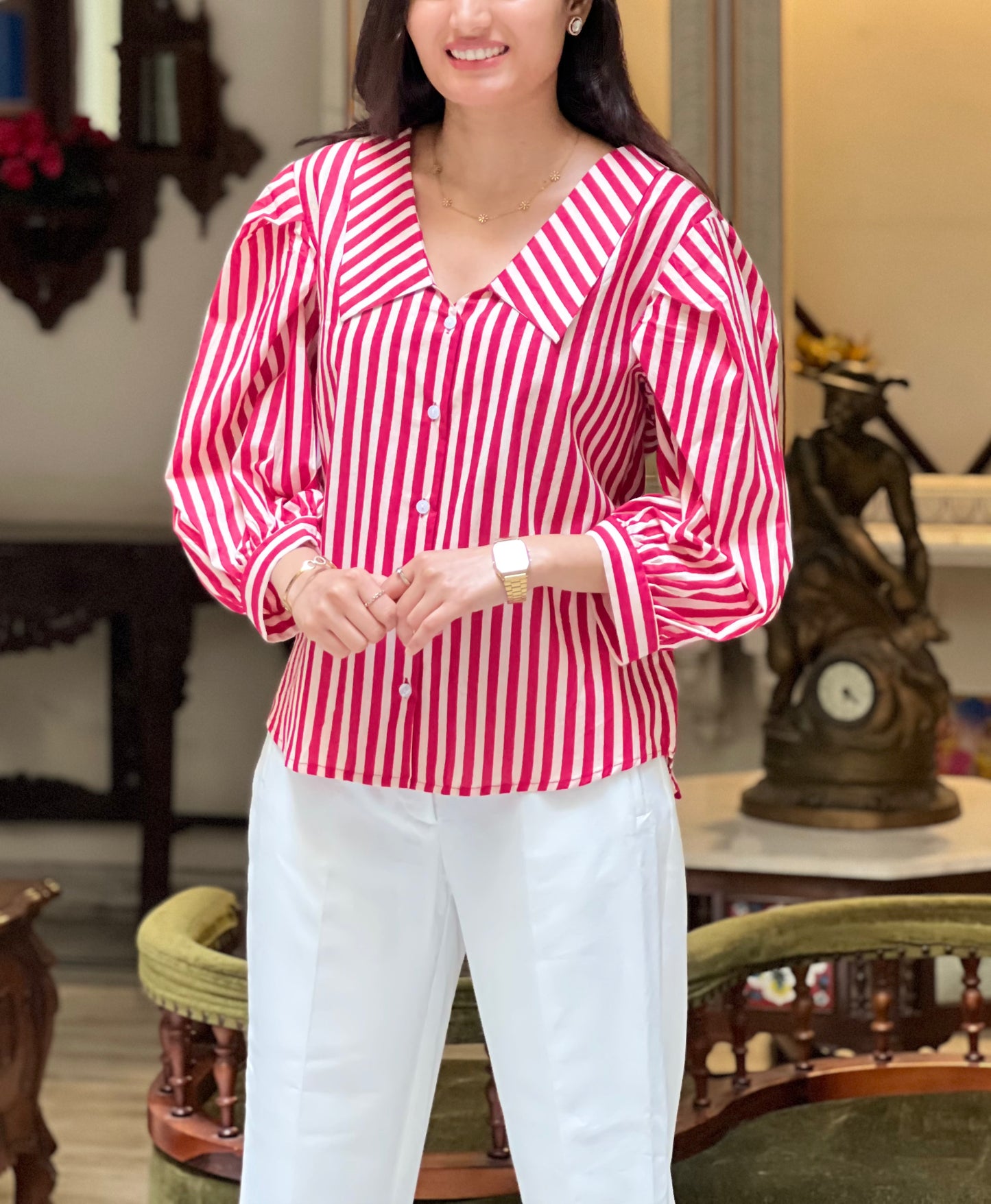 Woman wearing a red and white striped blouse and white pants in an indoor setting.