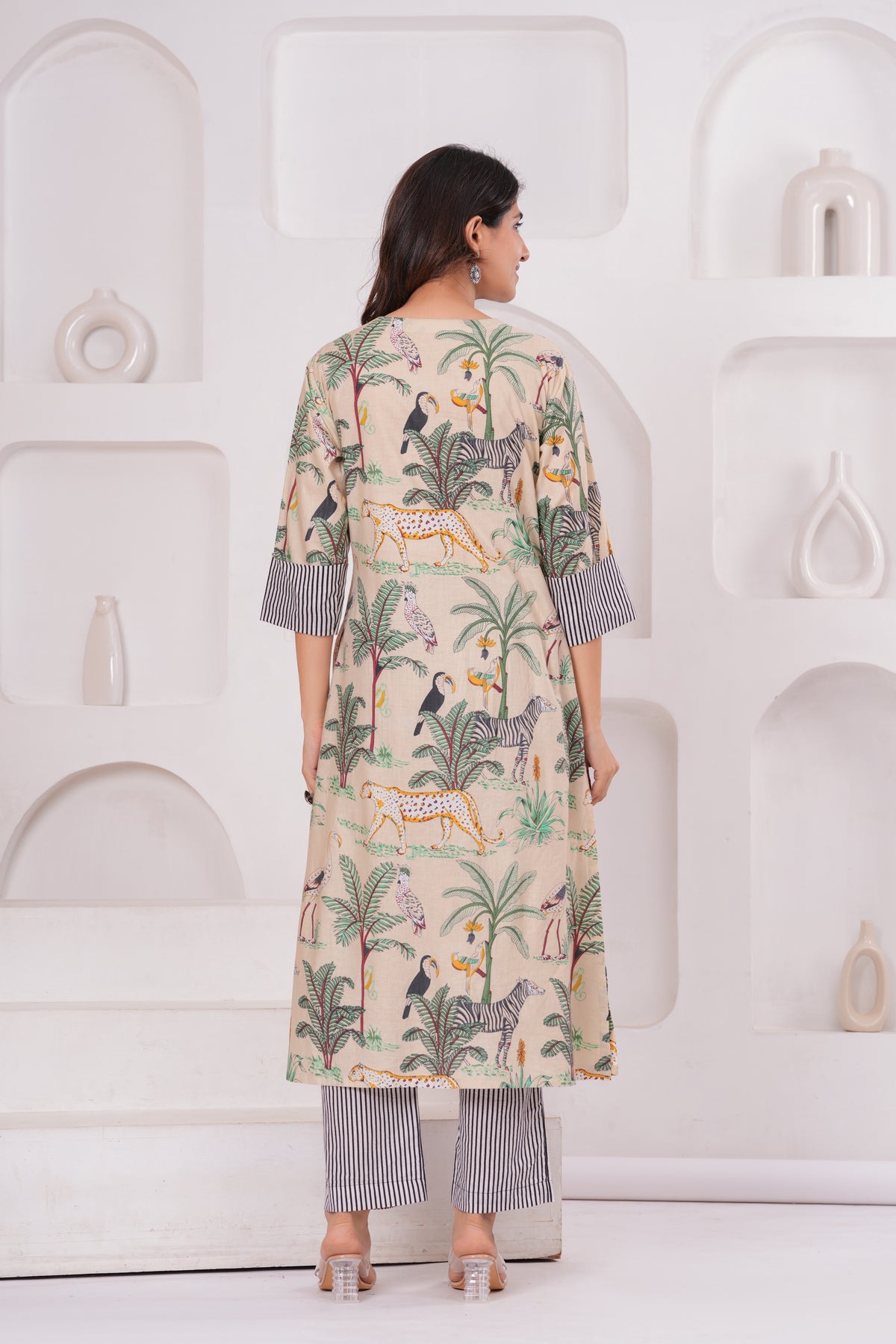 Woman wearing a patterned kurta with palampore design against a white wall.