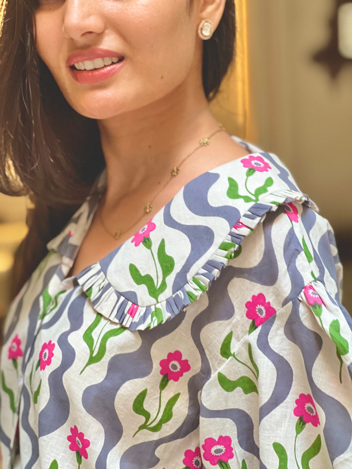 Woman wearing a patterned blouse with floral designs.