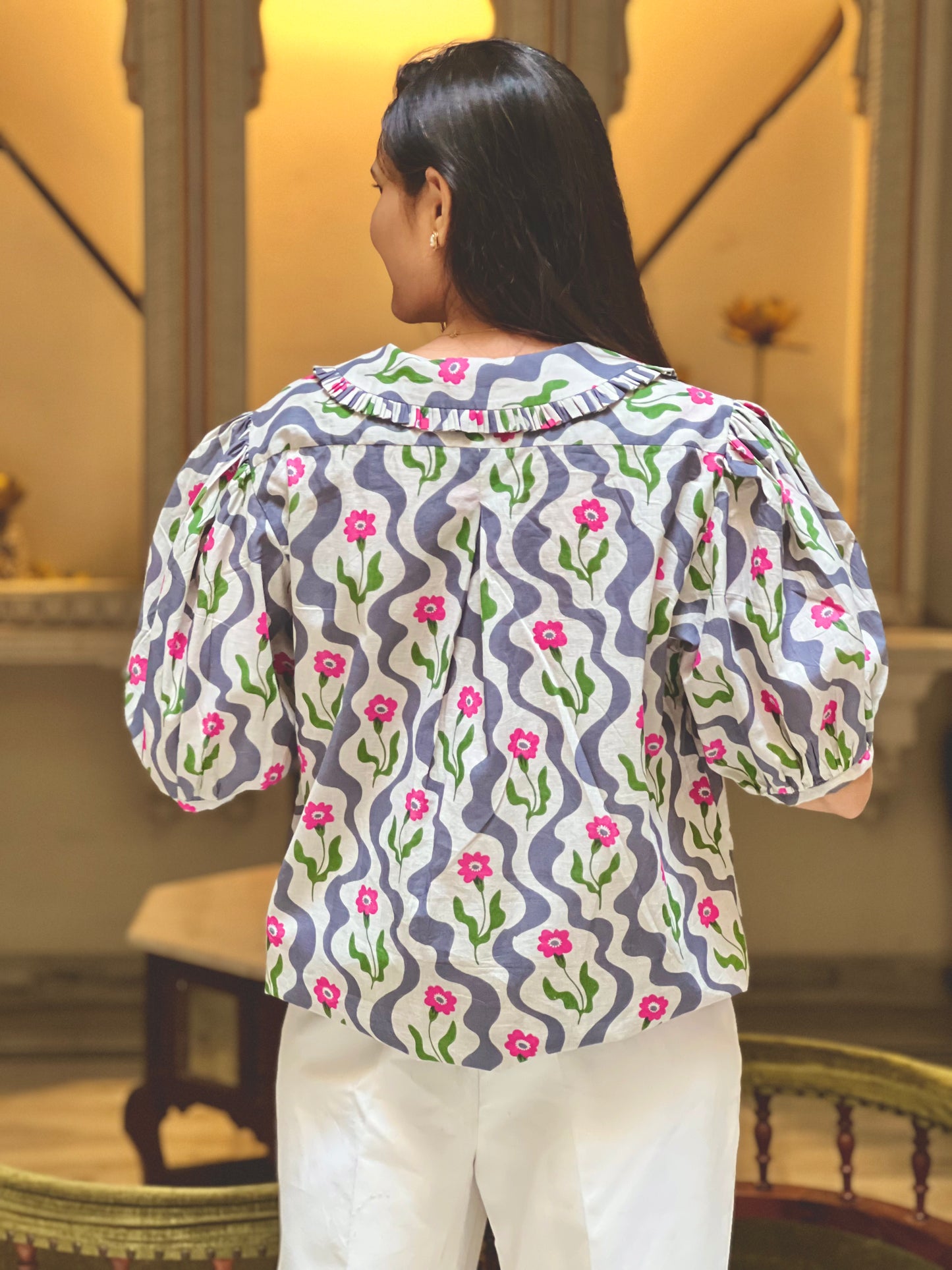 Woman wearing a patterned blouse with floral design in an indoor setting