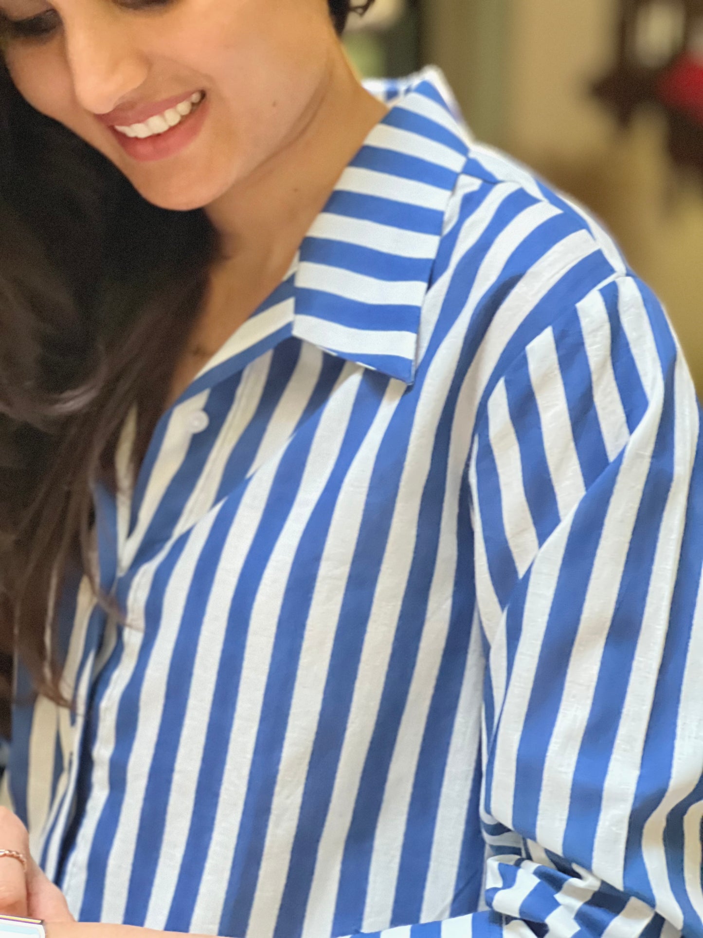 Woman wearing a blue and white striped shirt indoors.