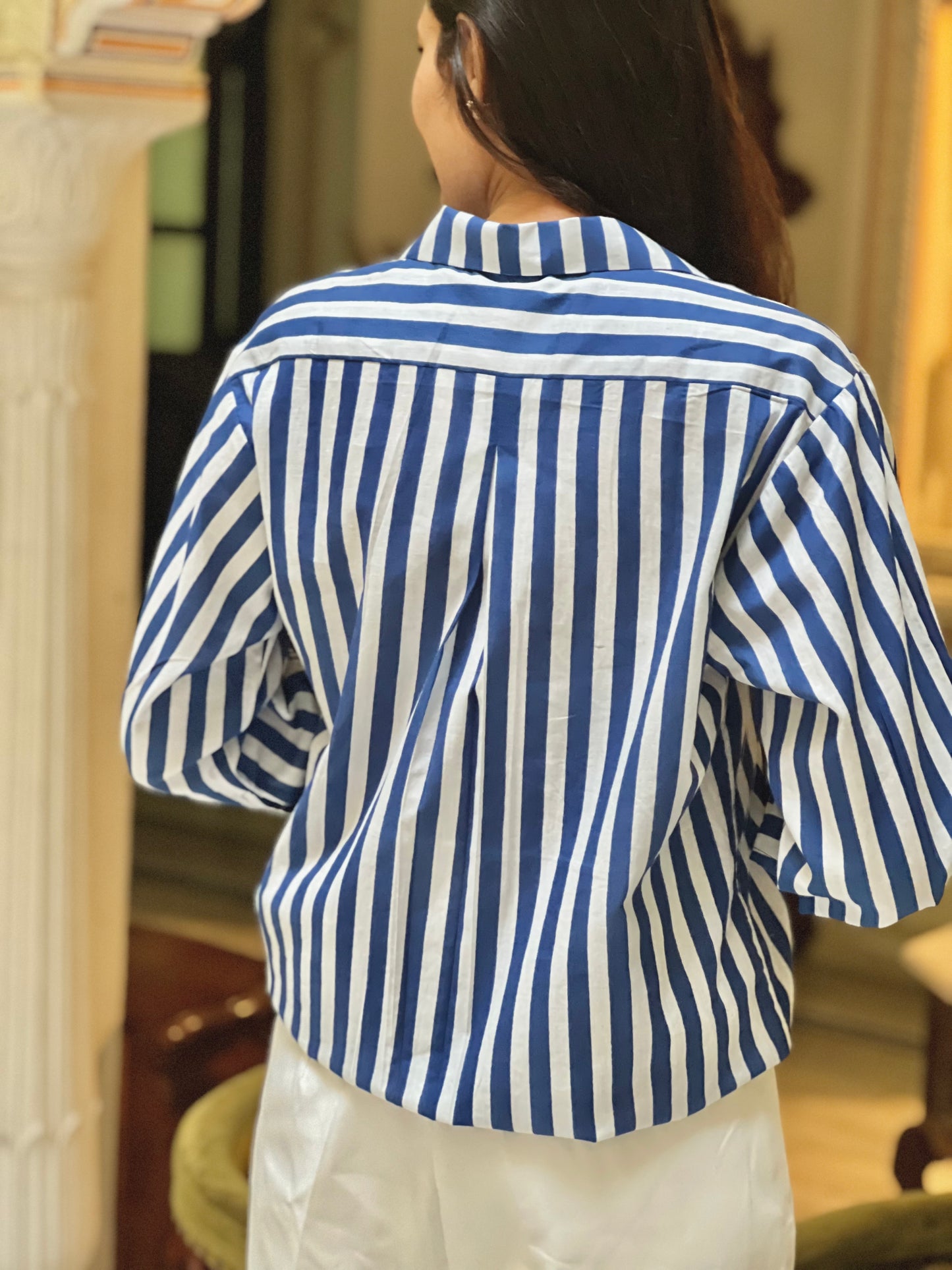 Person wearing a blue and white striped shirt in an indoor setting