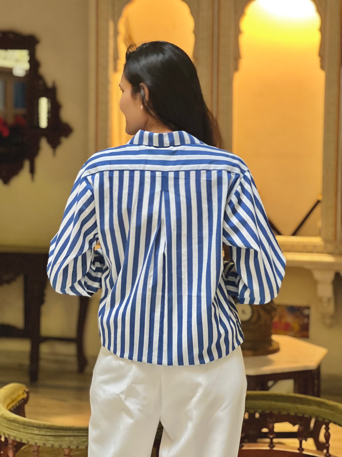 Person wearing a blue and white striped shirt in an indoor setting