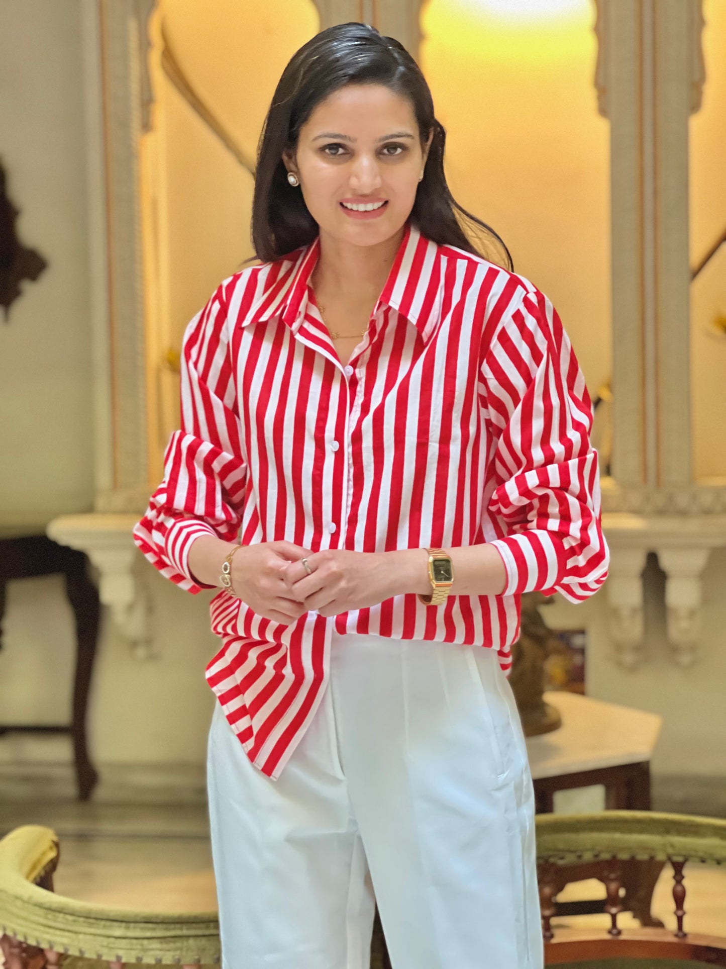 Woman wearing a red and white striped shirt and white pants in an indoor setting.