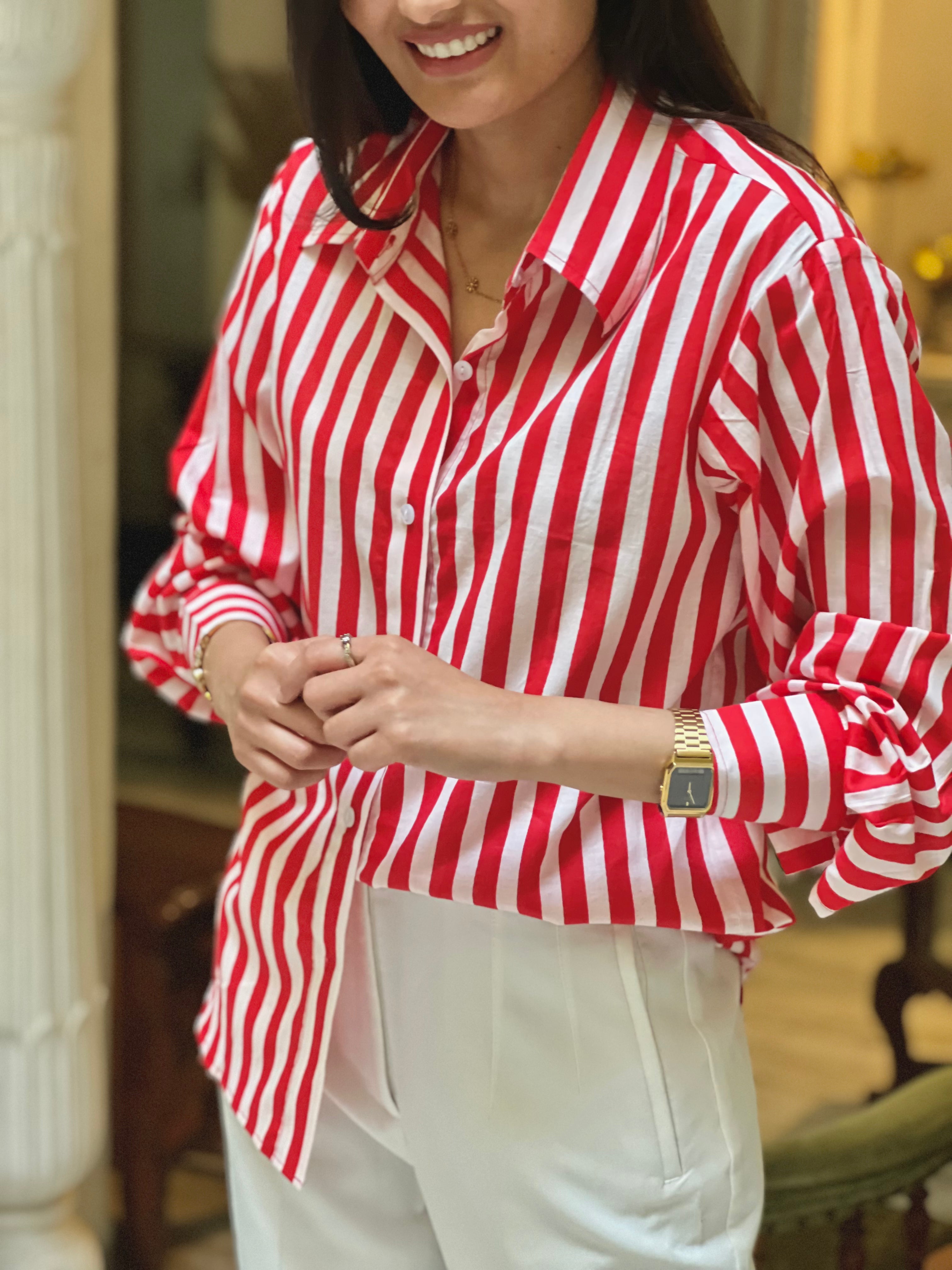 Person wearing a red and white striped shirt with white pants indoors.