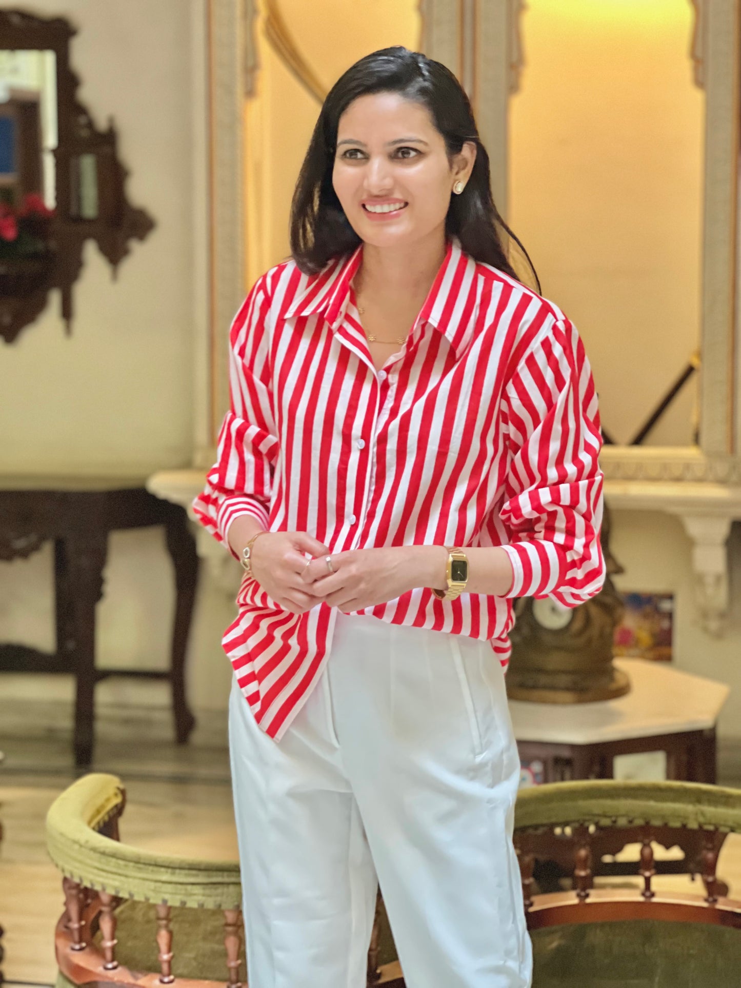 Woman wearing a red and white striped shirt and white pants in an indoor setting.