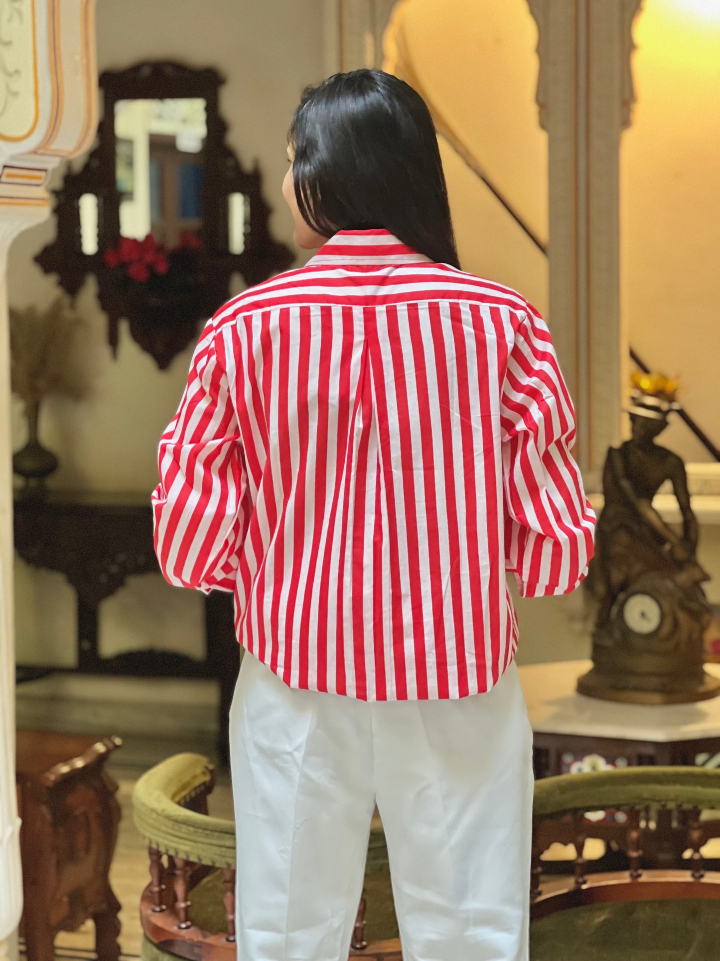 Person wearing a red and white striped shirt in an indoor setting with decorative elements.