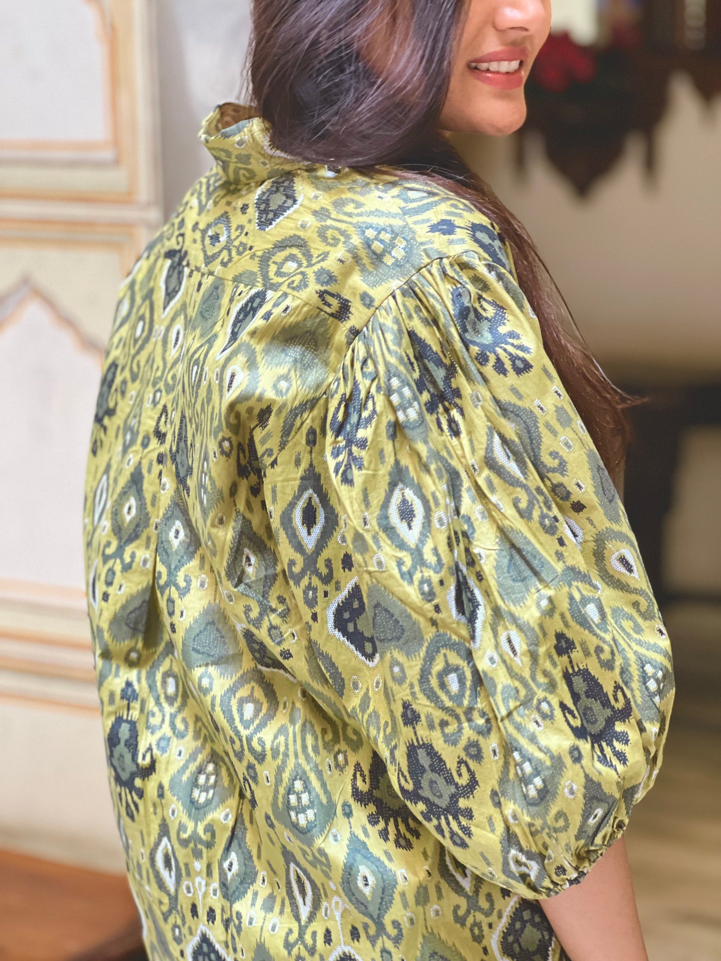 Woman wearing a green patterned blouse indoors