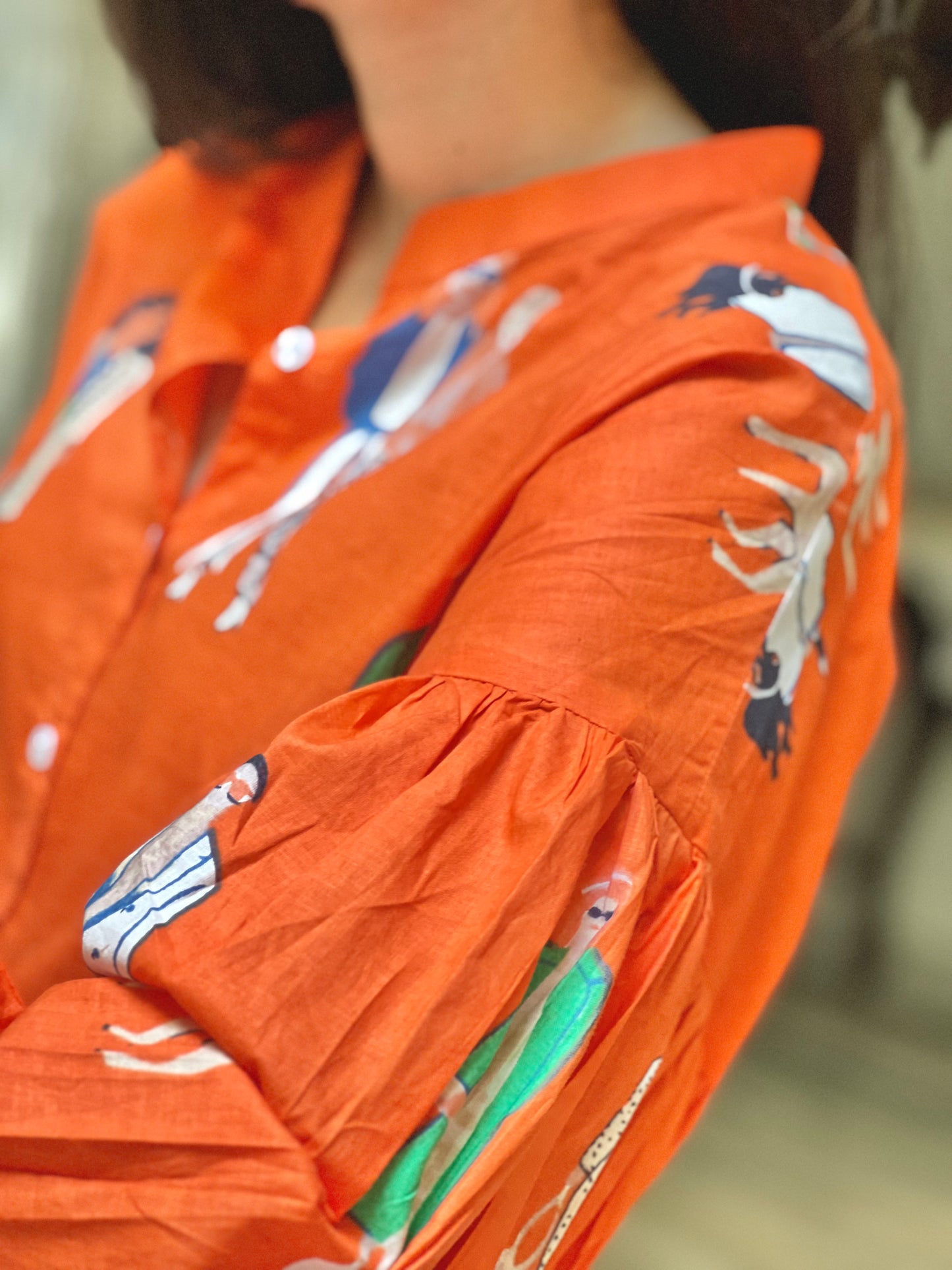 Close-up of an orange shirt with graphic designs on a blurred background