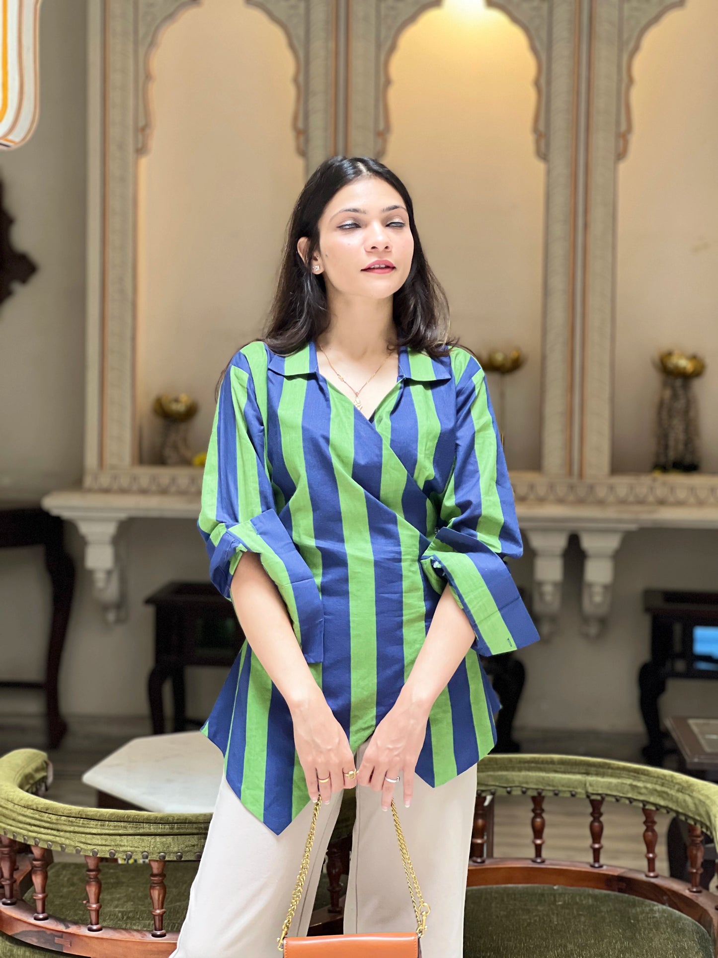 Woman wearing a blue and green striped shirt in an elegant interior setting