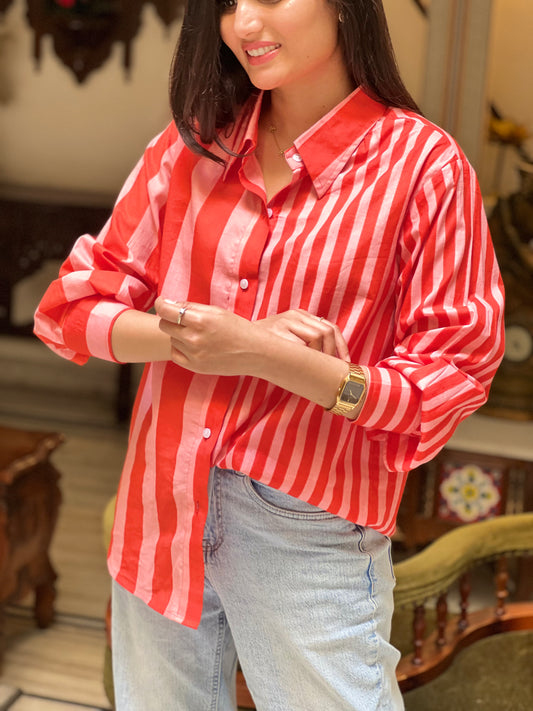 Woman wearing a red and white striped shirt and light blue jeans indoors.