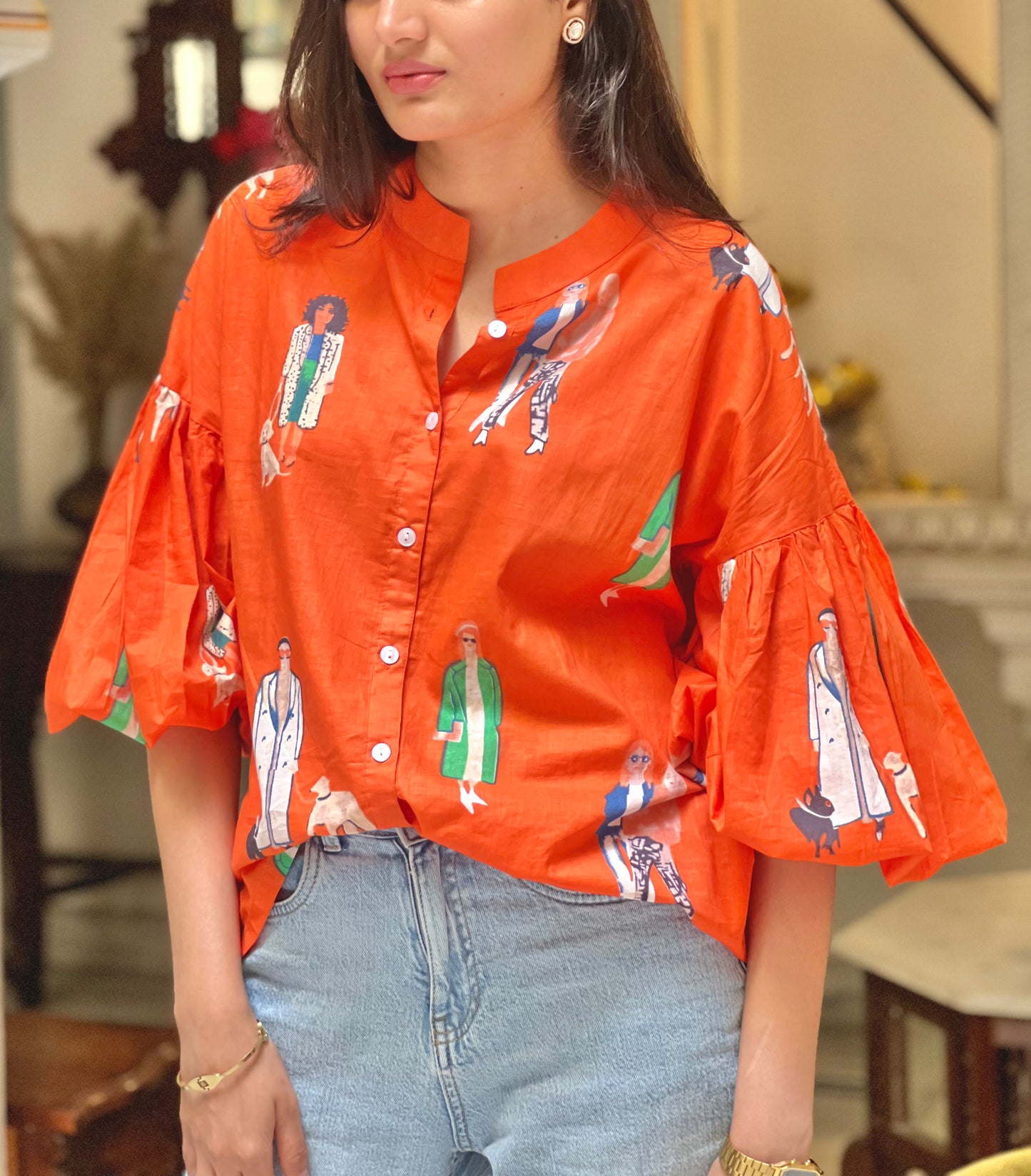 Person wearing an orange shirt with graphic designs in a casual setting