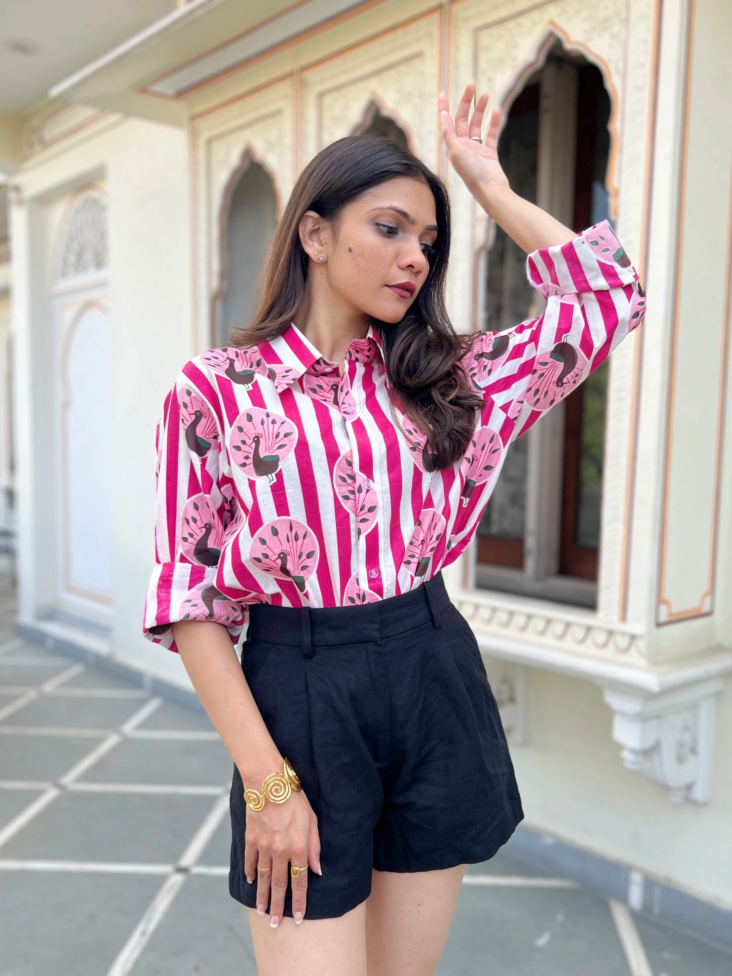 Woman wearing a pink and white striped shirt with black shorts in an outdoor setting.