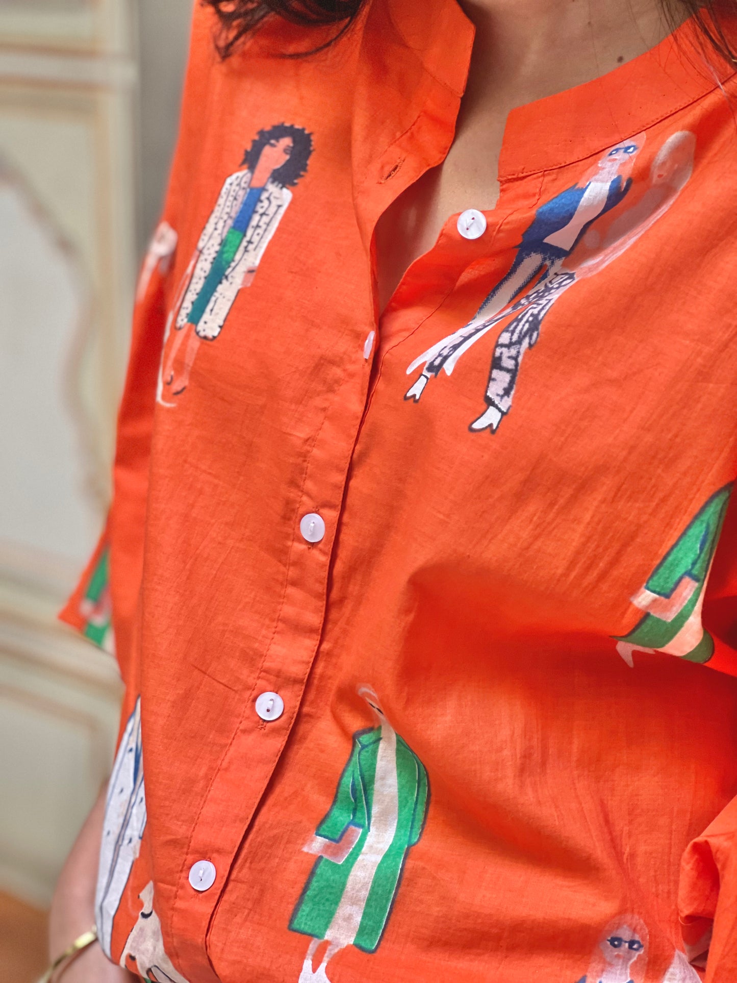 Orange shirt with colorful graphic designs on a blurred background