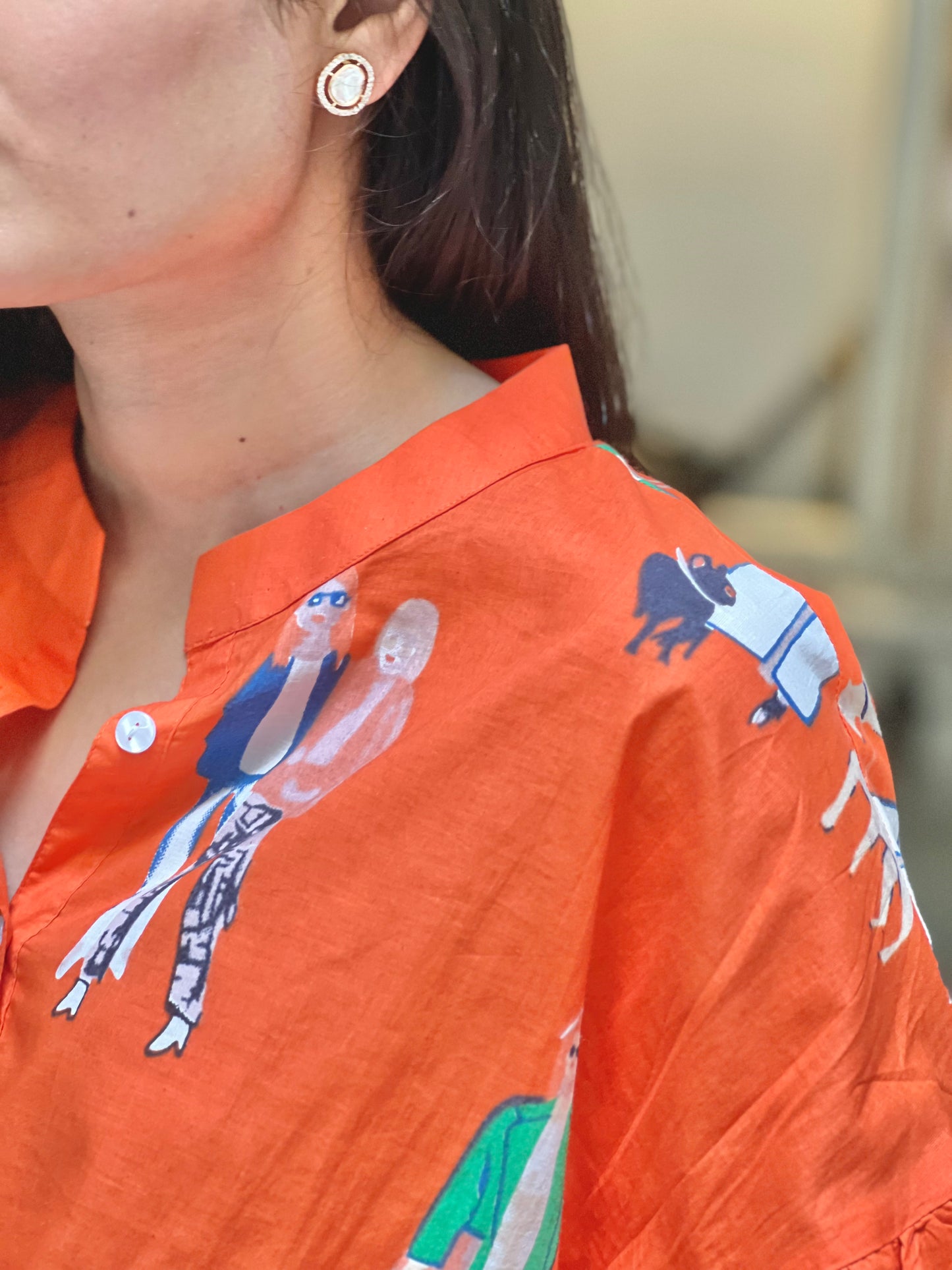 Person wearing an orange shirt with graphic designs, focusing on the collar and shoulder area.