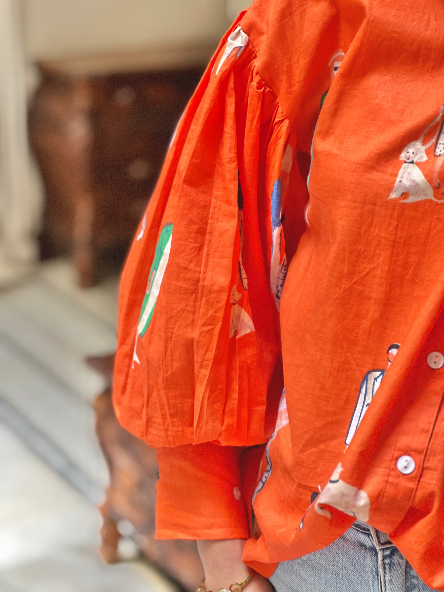 Close-up of an orange shirt with cartoon character print worn by a person.