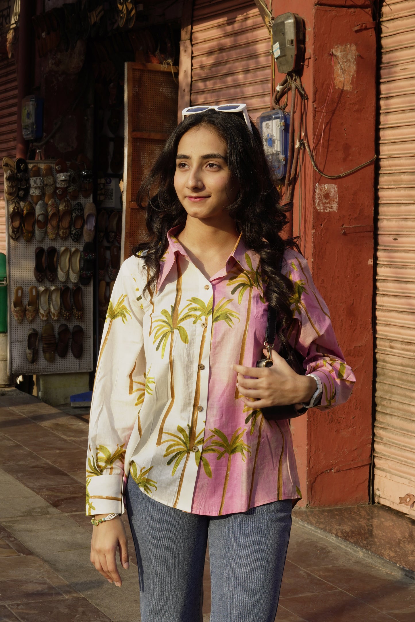 Woman lying on a suitcase with a floral shirt in an indoor setting