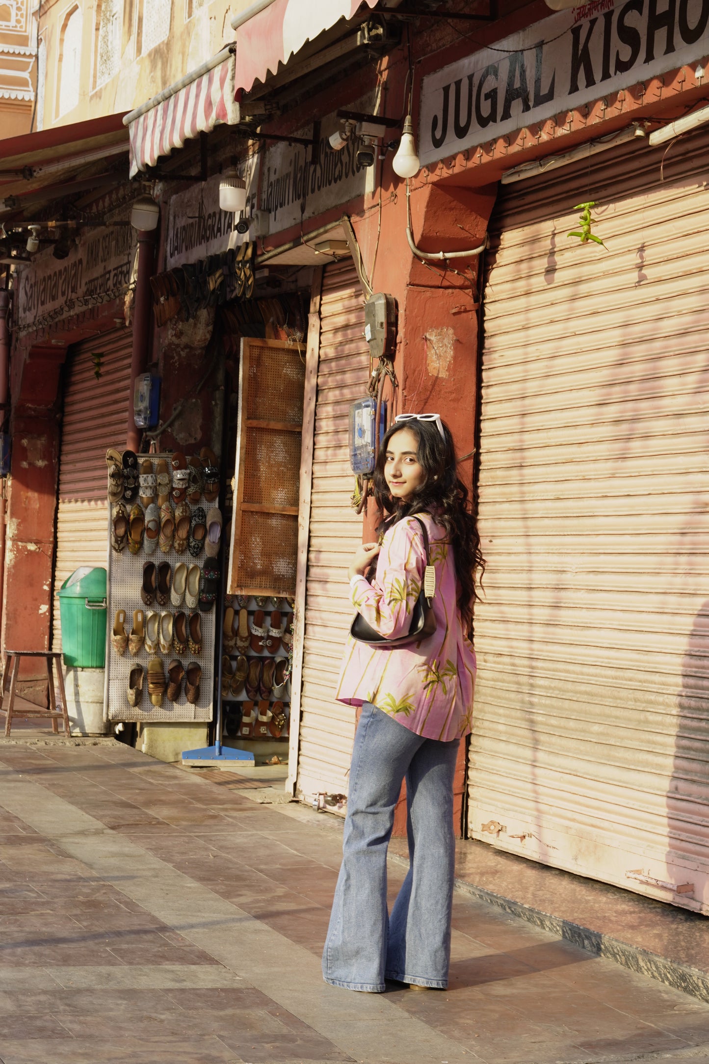 Woman standing in front of a closed shop with 'Jugal Kishore' sign on a street.