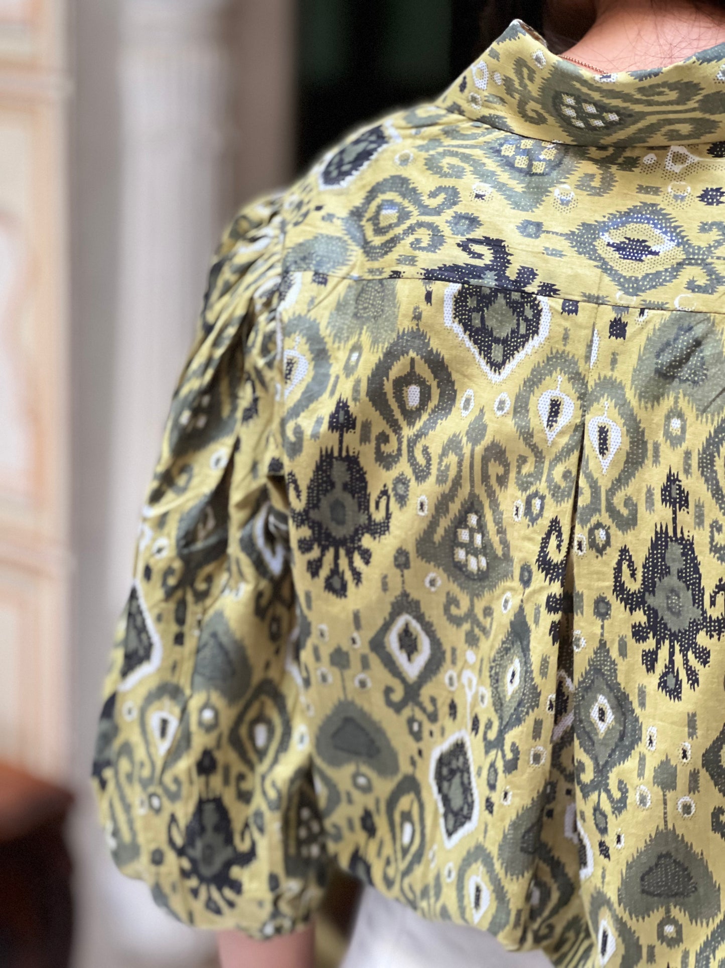 Close-up of a person wearing a patterned shirt with a blurred background