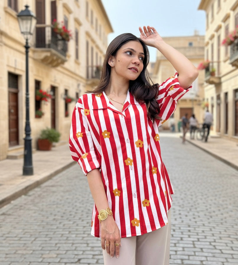 Woman wearing a red and white striped shirt with floral patterns on a street.