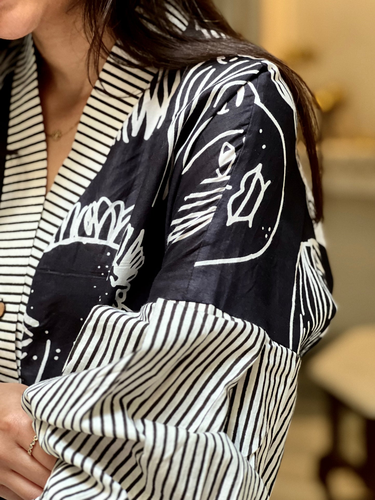 Close-up of a person wearing a black and white patterned shirt with a blurred background