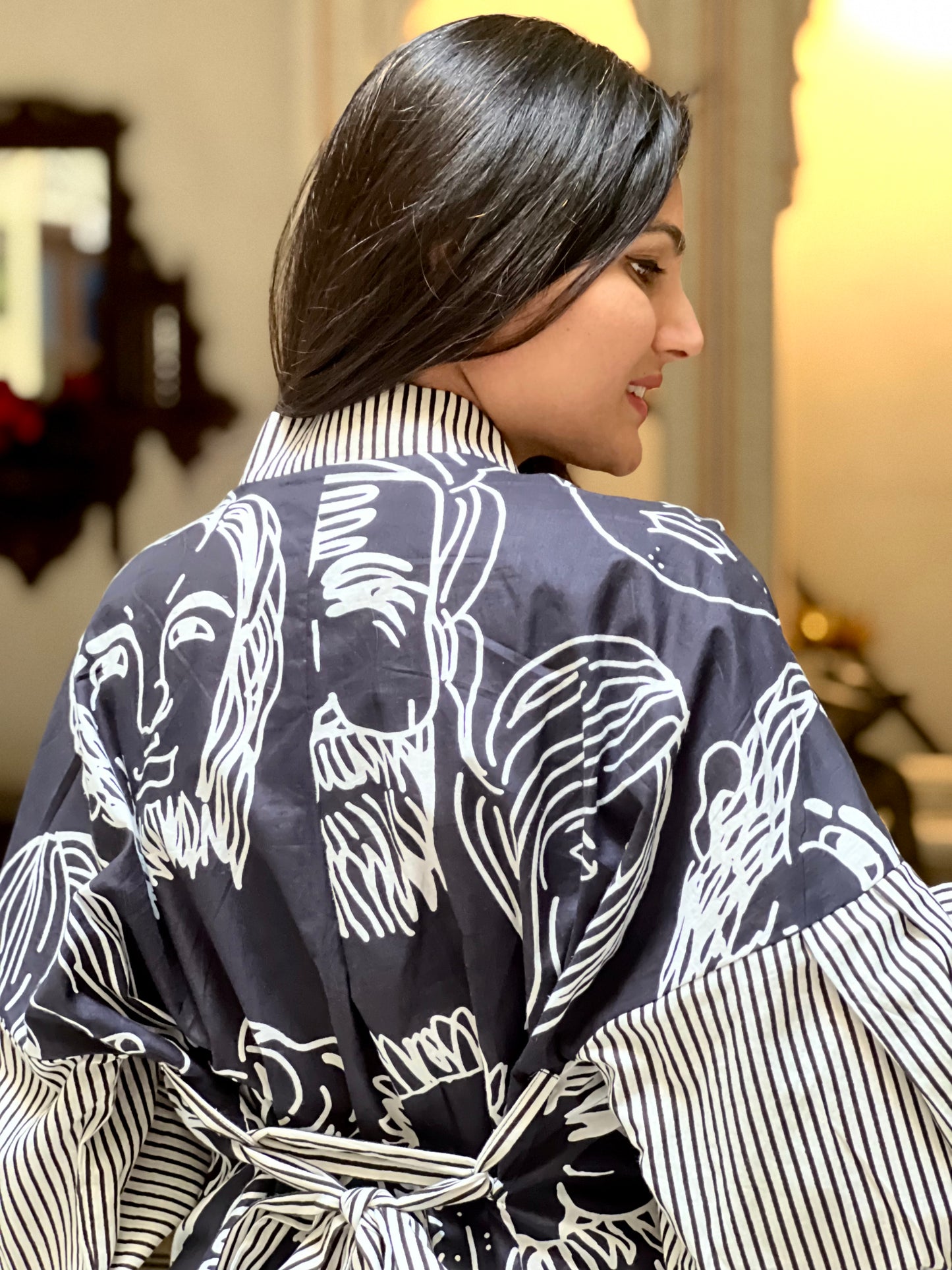 Woman wearing a black and white patterned robe in a room with decorative elements.