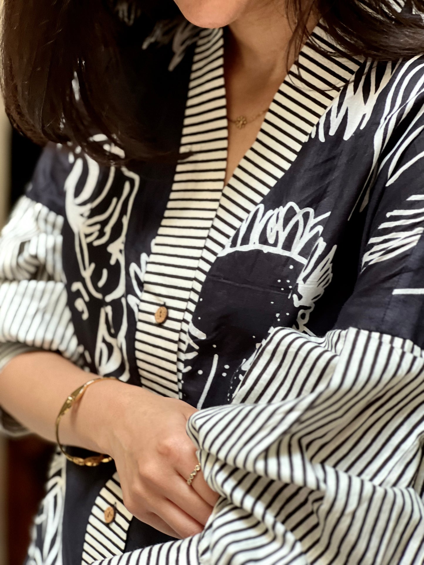 Close-up of a person wearing a black and white patterned outfit with a focus on the collar and sleeves.