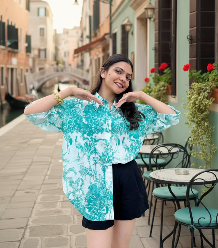Woman posing in a scenic outdoor setting with a canal and buildings.