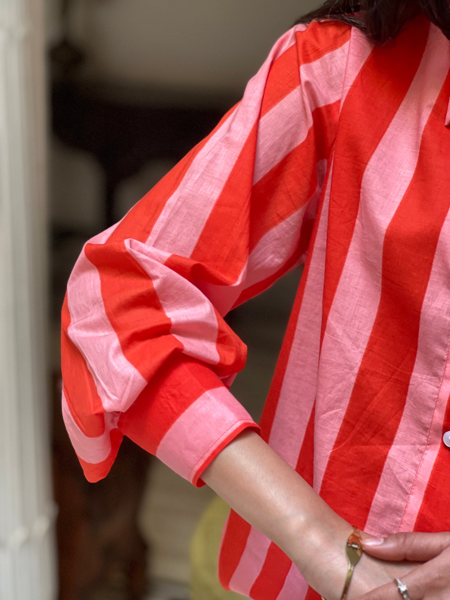Red and pink striped shirt worn by a person, with a blurred background
