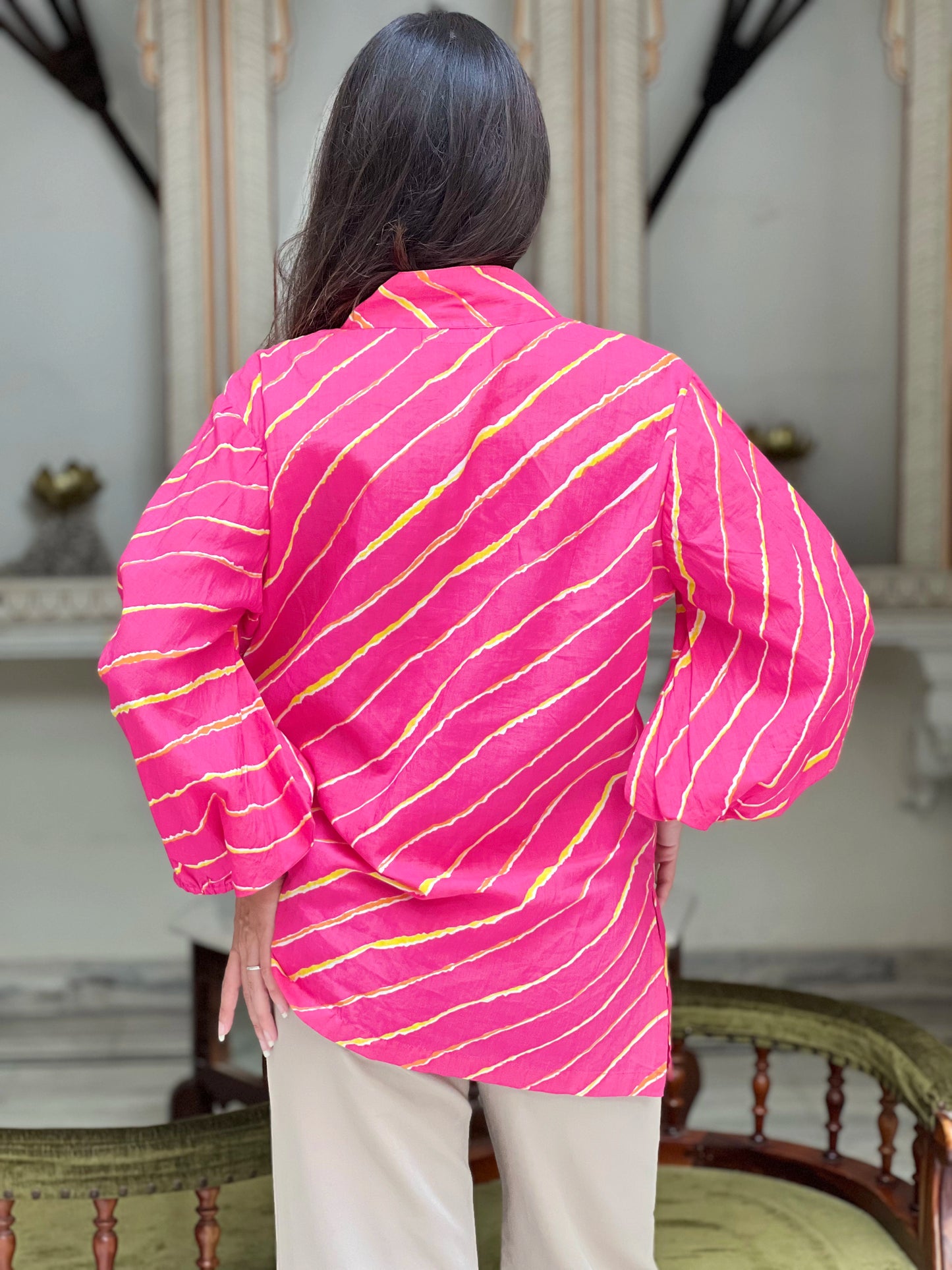 Person wearing a bright pink shirt with yellow stripes in an indoor setting