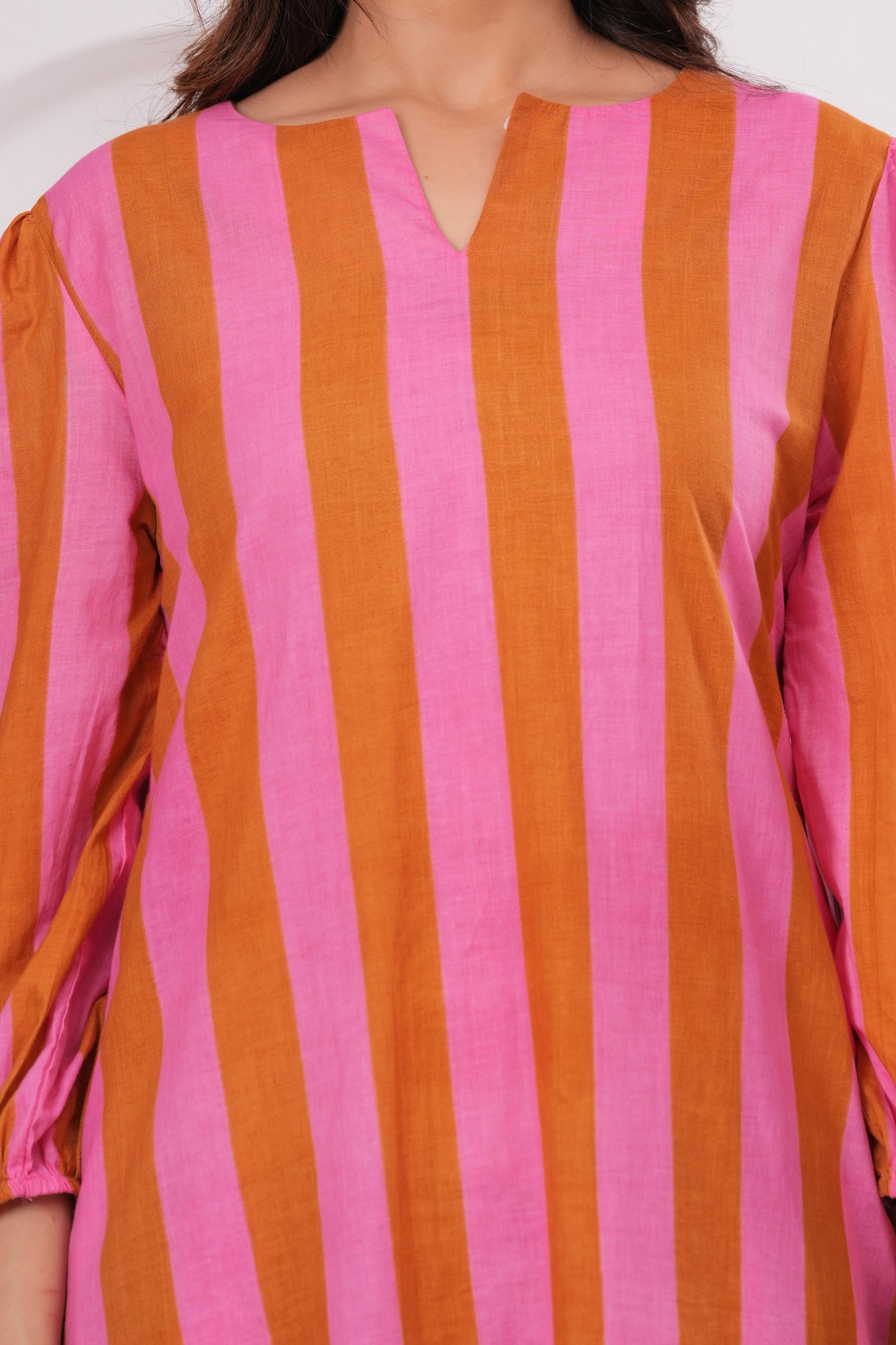 Close-up of a person wearing a pink and orange striped shirt.