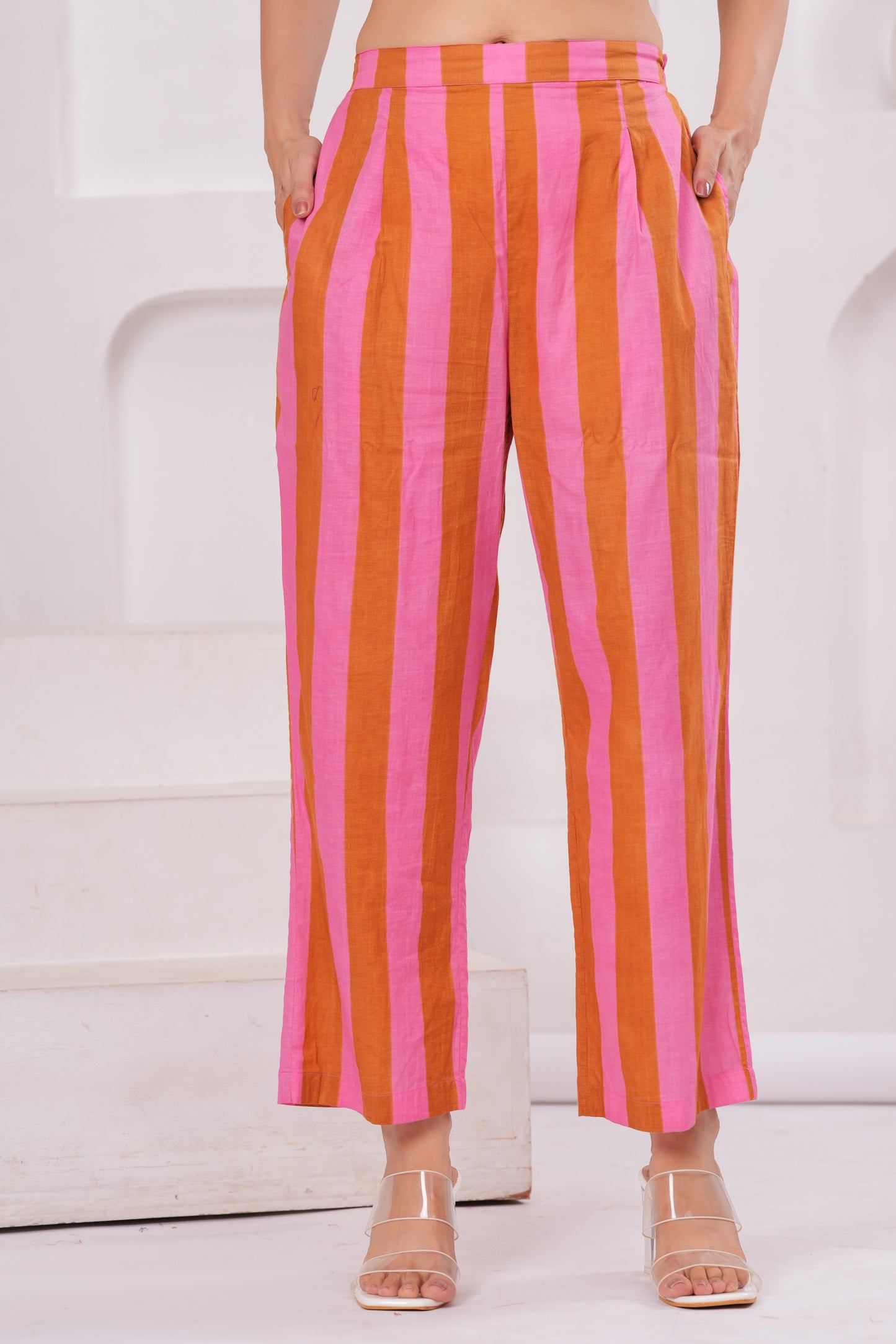 Person wearing pink and orange striped pants on a white background