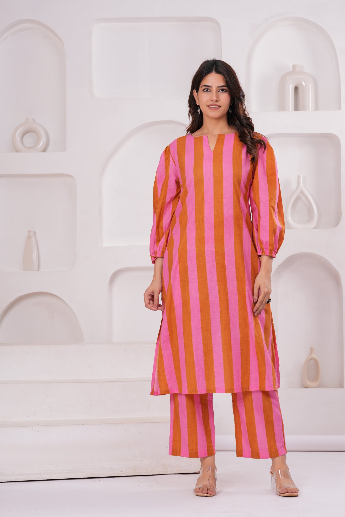 Woman wearing a pink and orange striped outfit against a white background