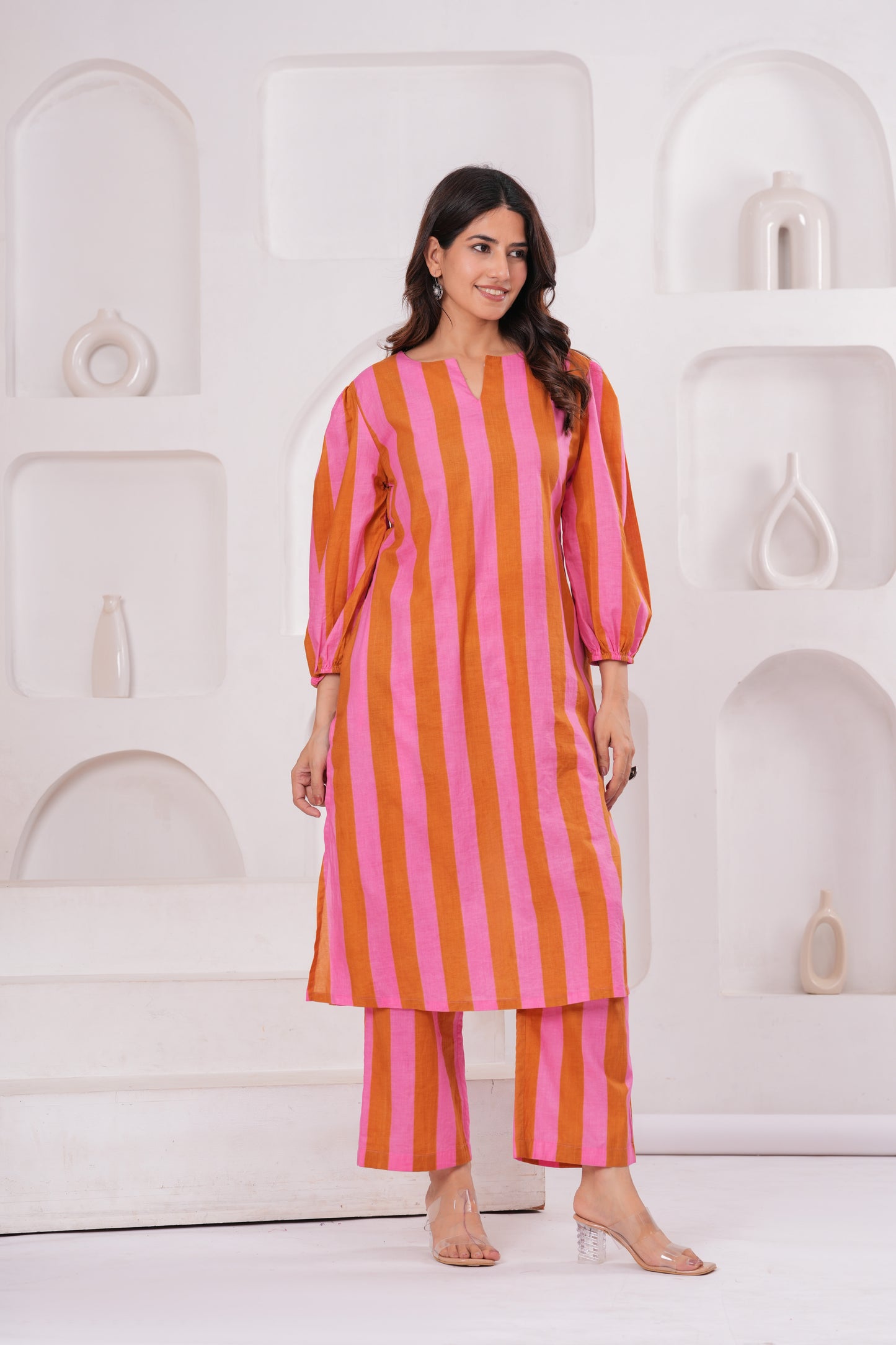 Woman wearing a pink and orange striped outfit against a white background