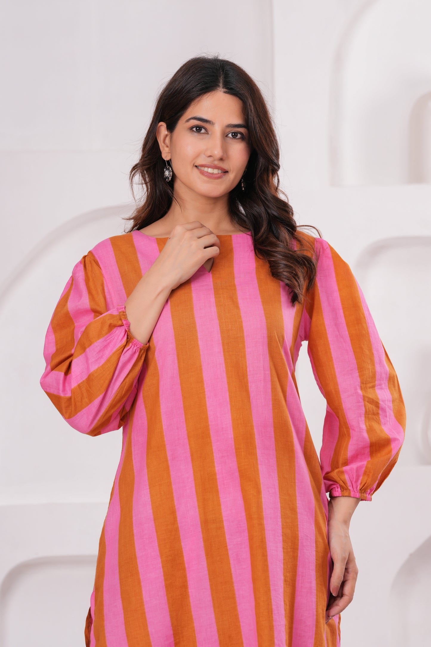 Woman wearing a pink and orange striped dress against a white background