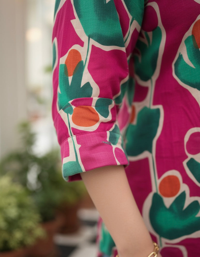 Colorful floral dress with pink, green, and orange pattern on a blurred indoor background