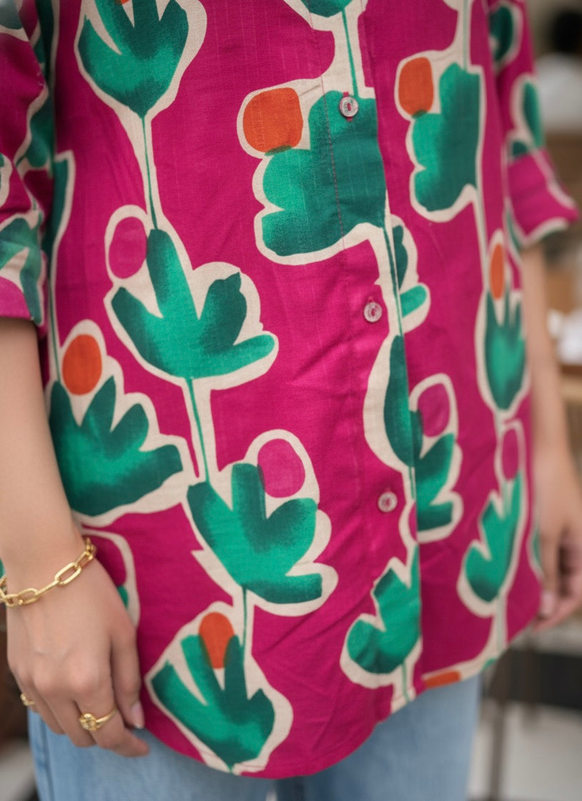 Person wearing a vibrant pink shirt with green leaf patterns.