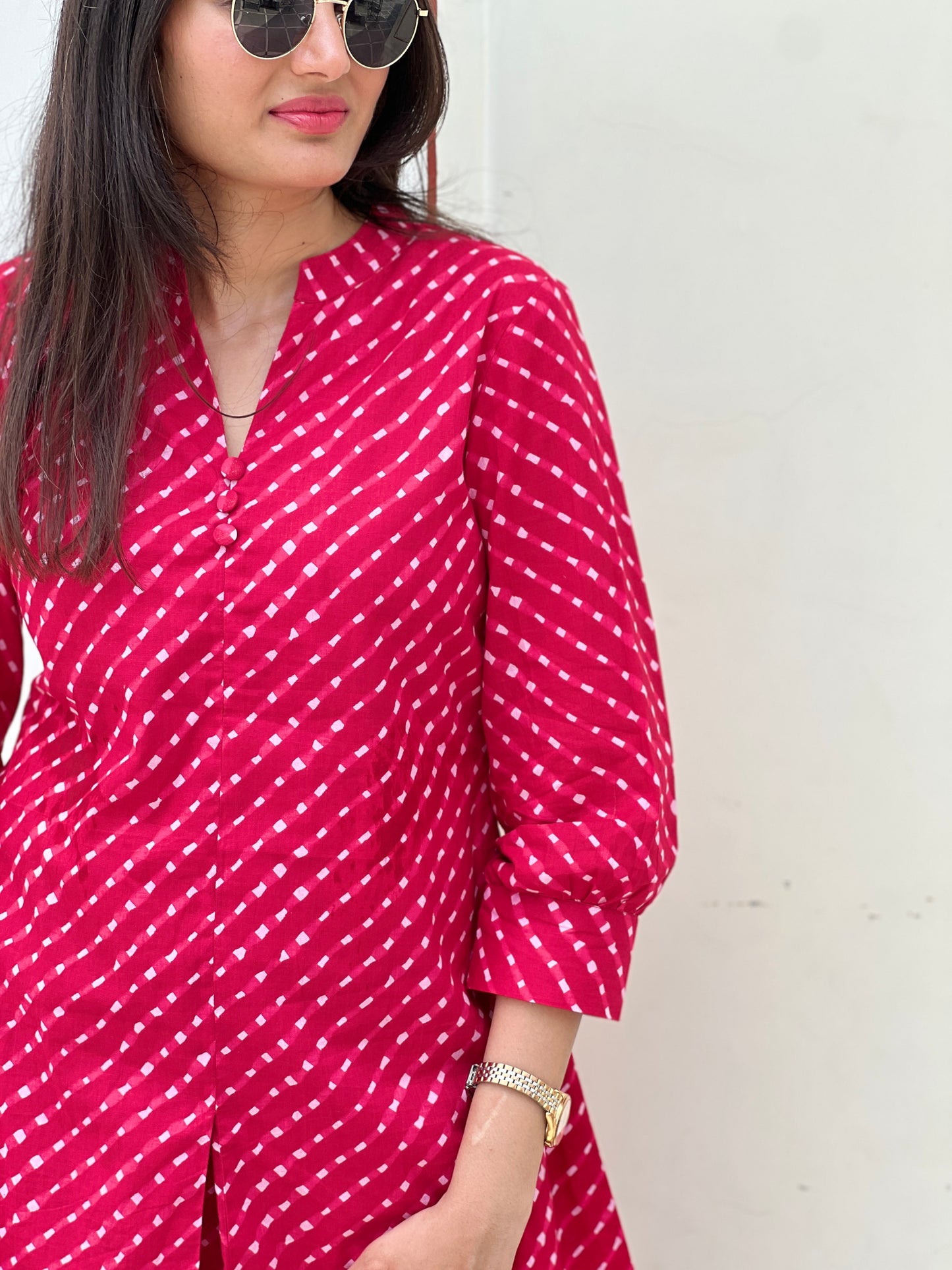 Woman wearing a red and white patterned outfit against a plain background