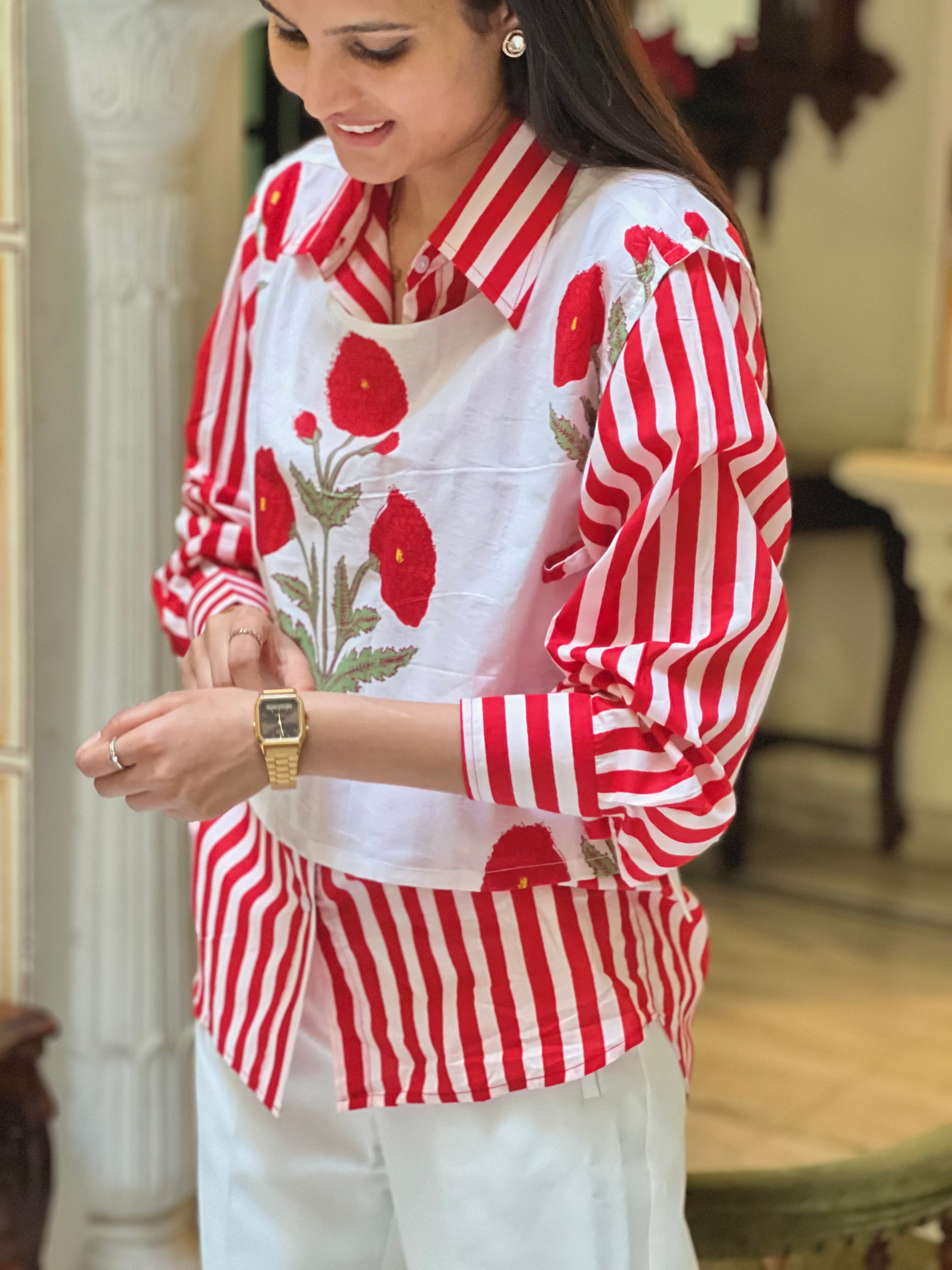 Woman wearing a red and white striped shirt with floral patterns indoors.