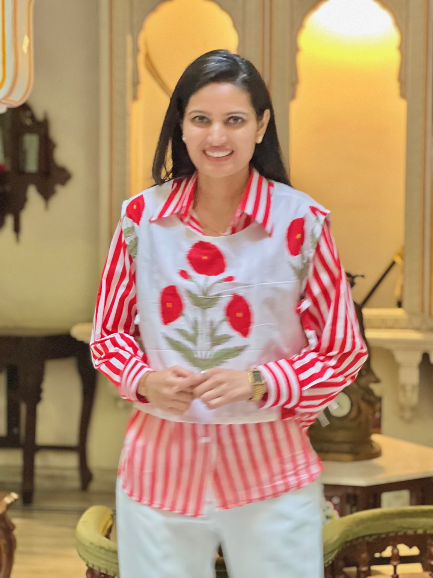 Woman wearing a red and white striped shirt with floral patterns indoors.