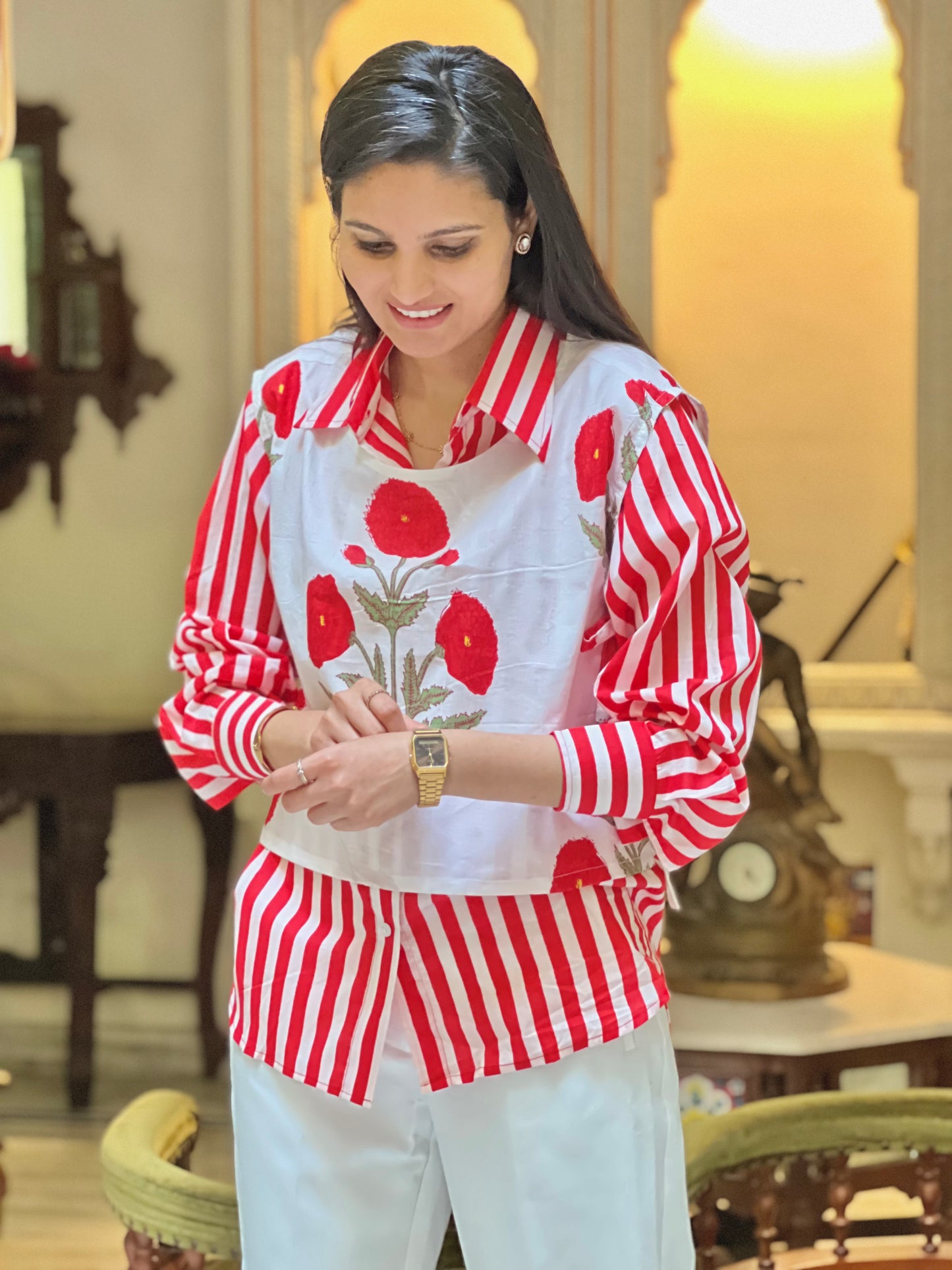 Woman wearing a red and white striped shirt with floral patterns in an indoor setting.