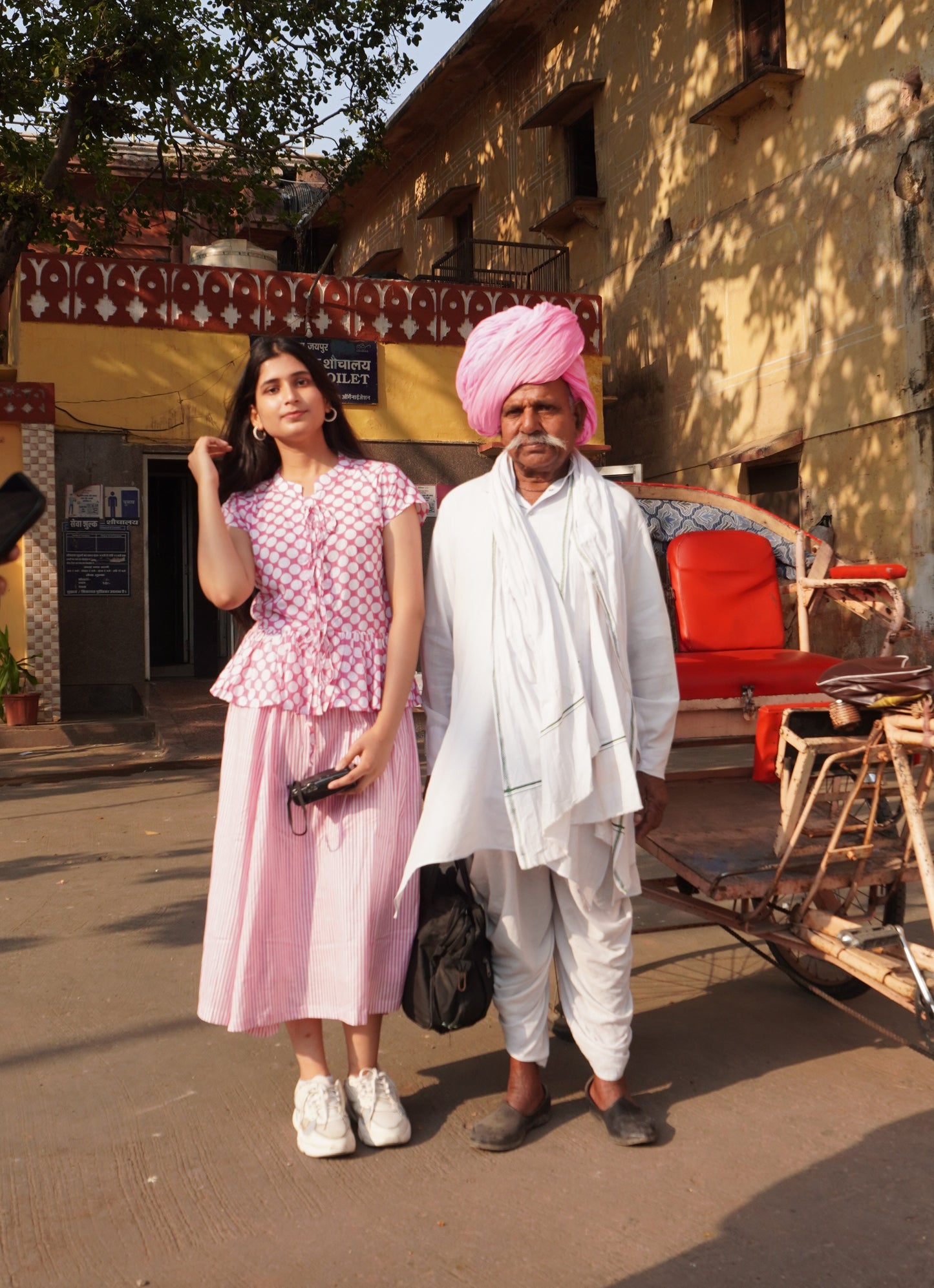 Two people standing on a street with a bicycle and cart in the foreground.