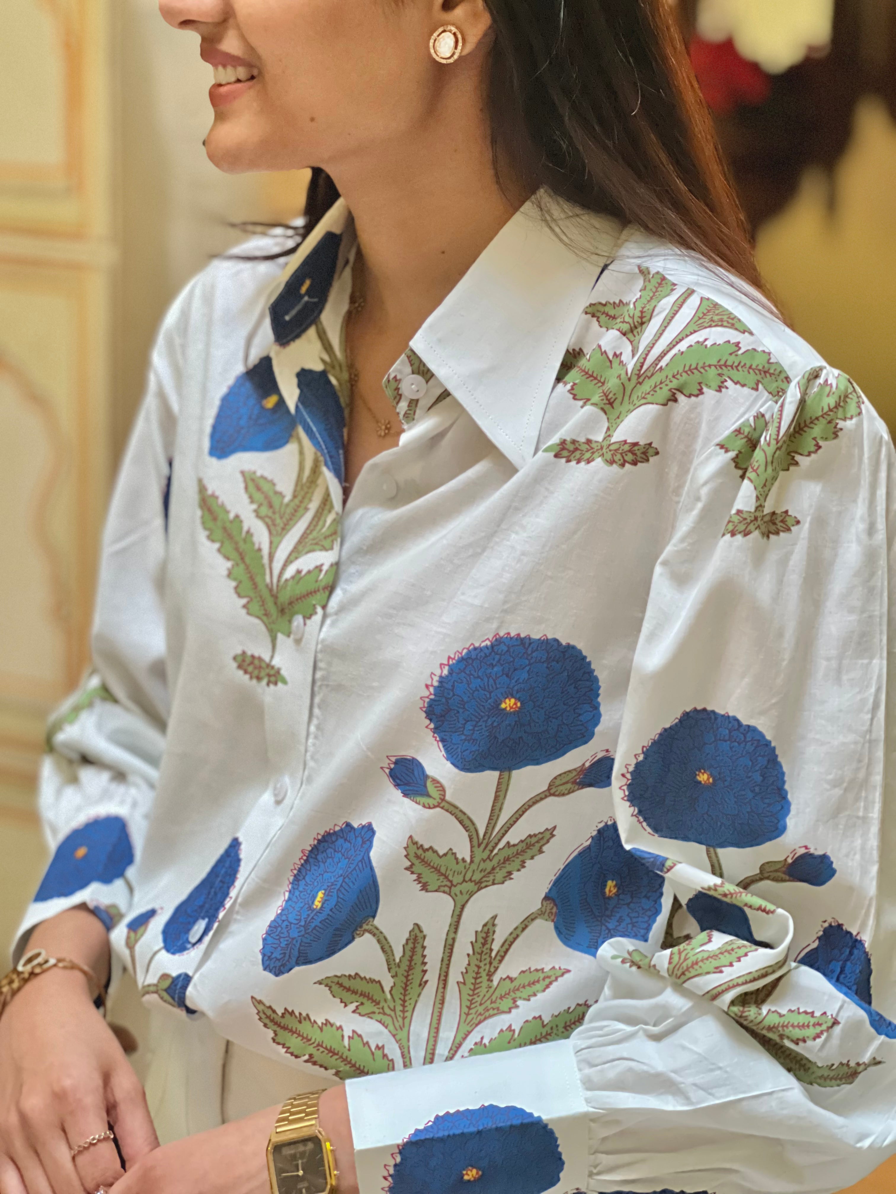 Woman wearing a white blouse with blue floral patterns in an indoor setting
