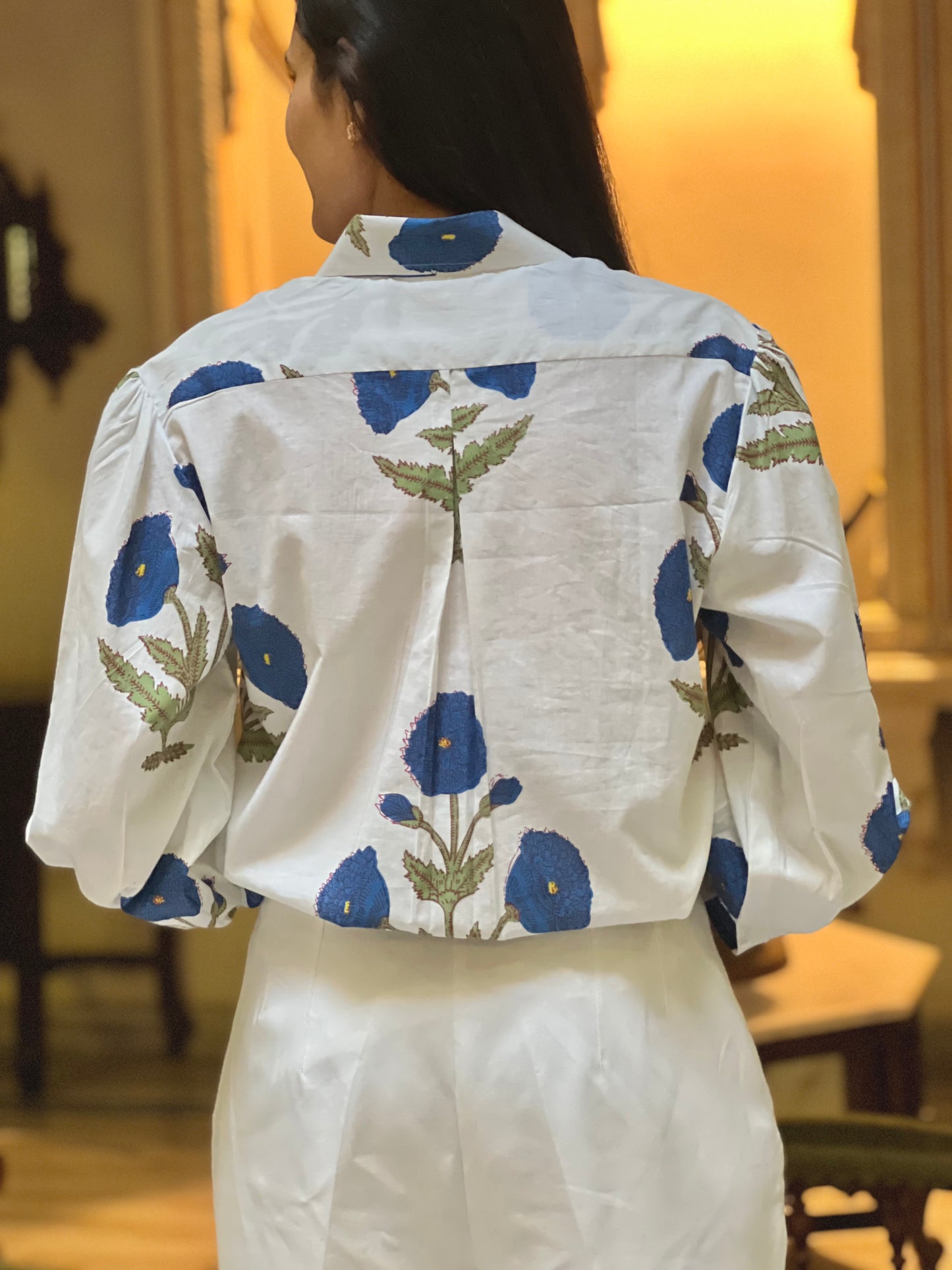 White blouse with blue floral patterns worn by a person indoors.