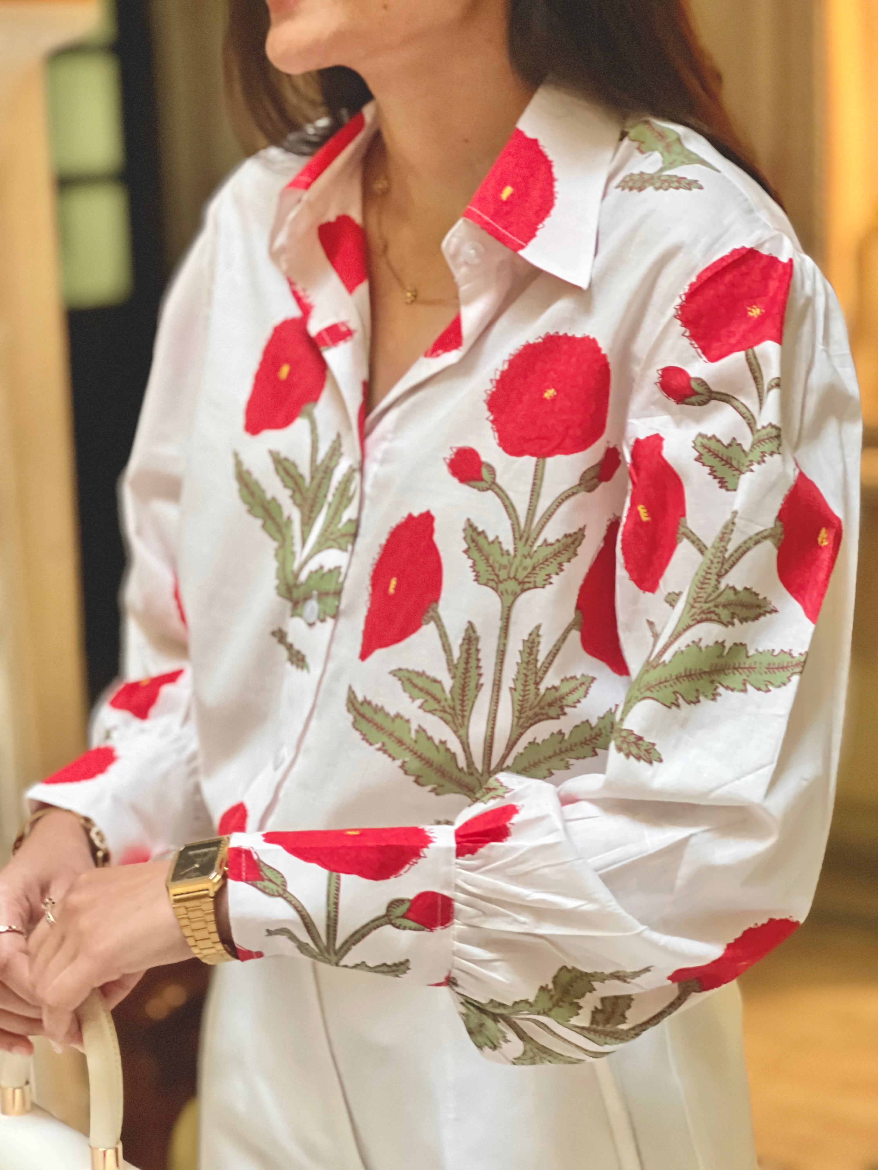 White blouse with red floral patterns worn by a person.
