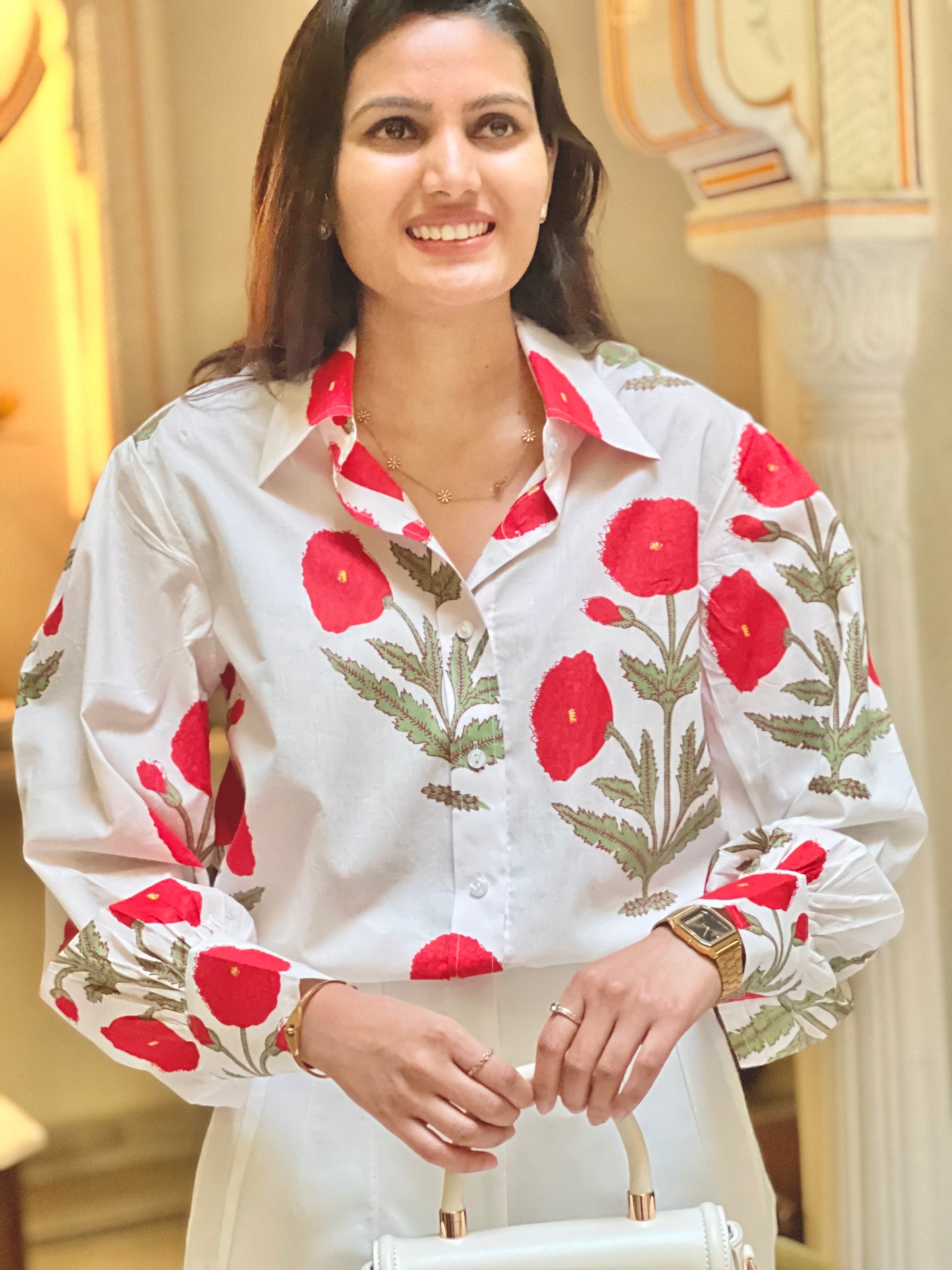Woman wearing a white blouse with red floral patterns in an indoor setting